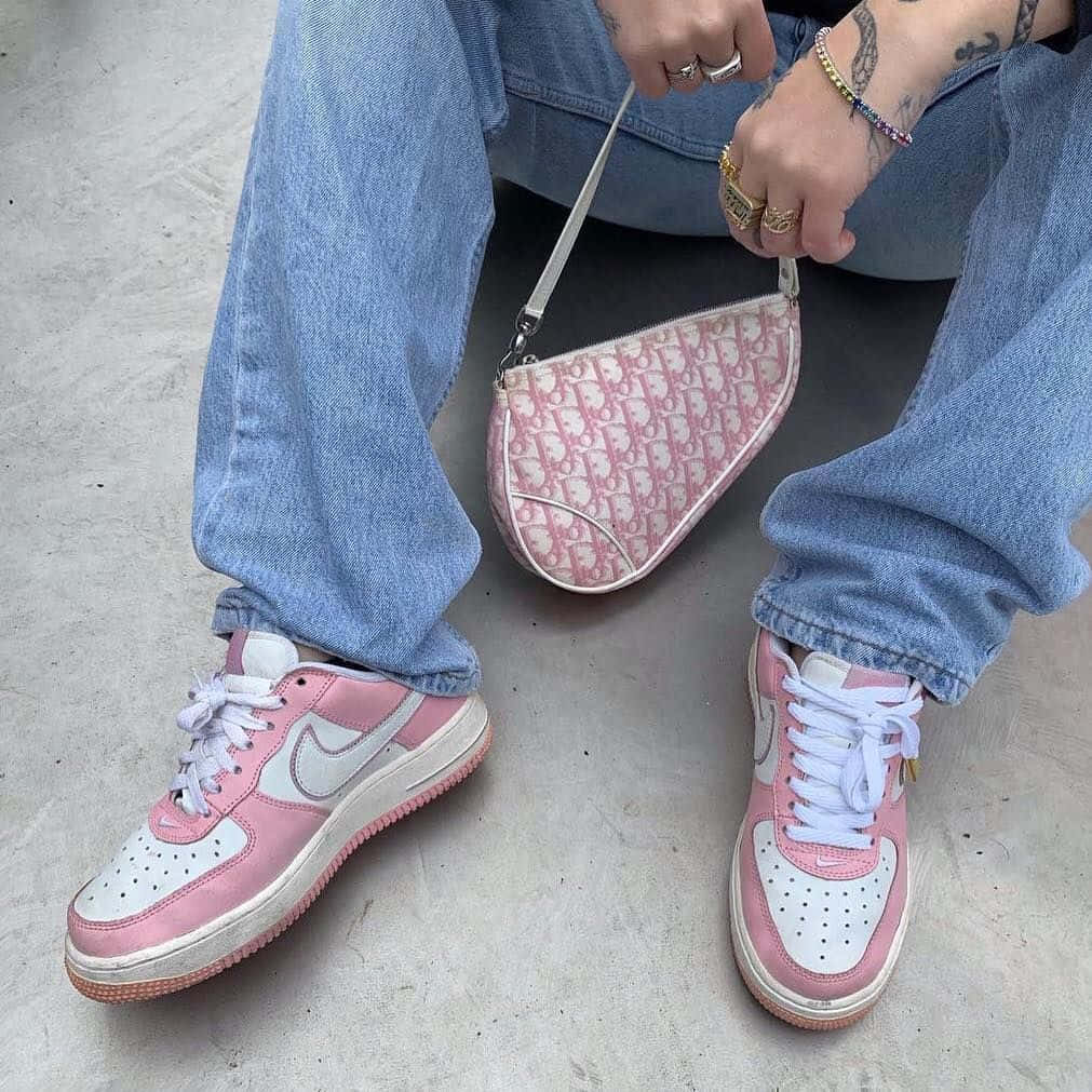 Pink Shoes 桌布 壁紙 — 特寫一個人穿著粉紅色和白色運動鞋配牛仔褲，在混凝土地上拿著一個粉紅色圖案手提包。