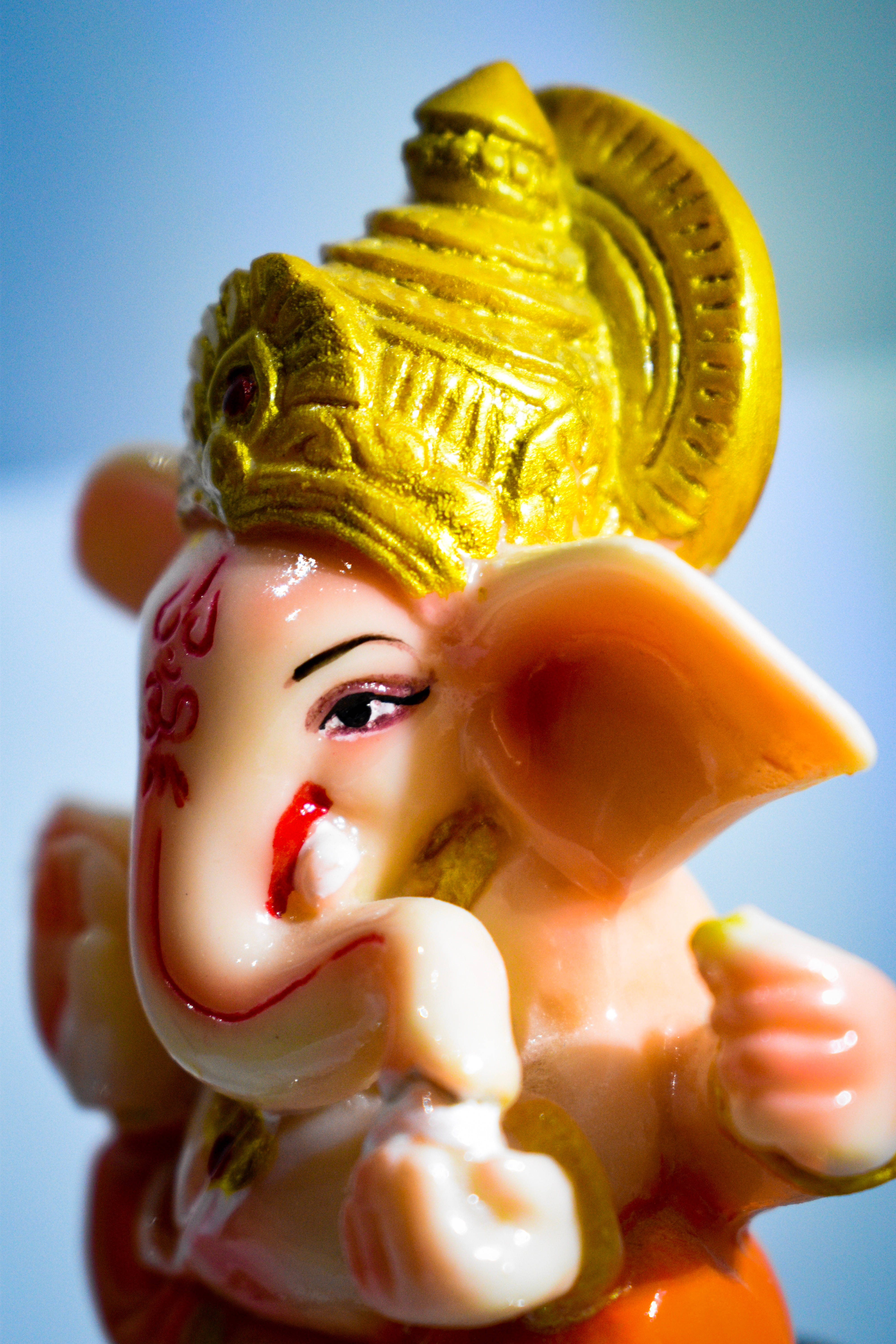 Lord Shiva 桌布 壁紙 — 特寫一個光澤粉紅色象頭神像，帶有金色皇冠和紅色標記，背景是柔和的藍色。