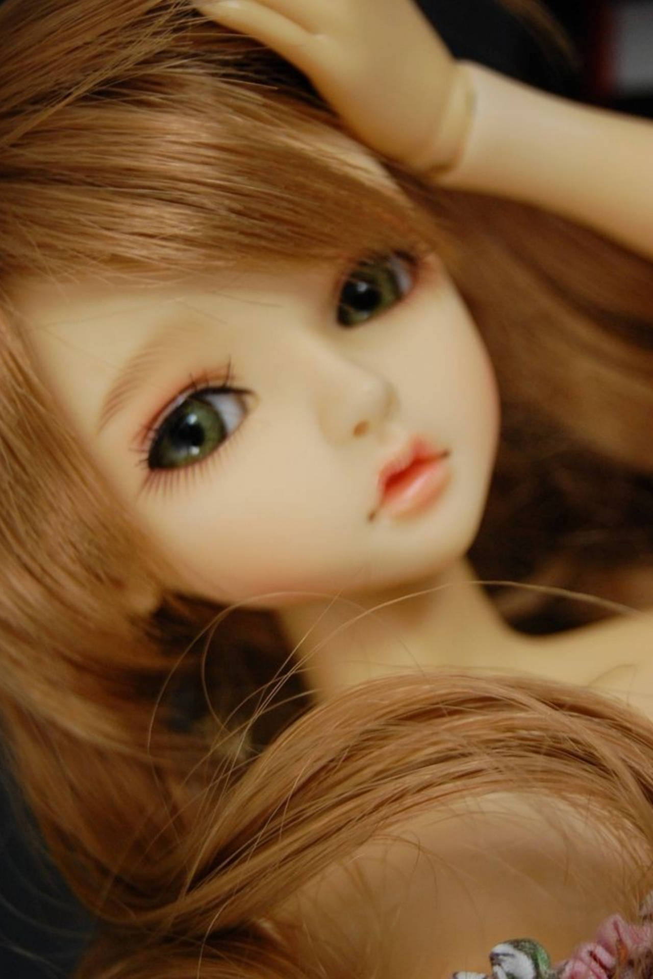 一個擁有綠色大眼睛和棕色頭髮的洋娃娃觸摸她的頭。 — 芭比 GIF 壁紙