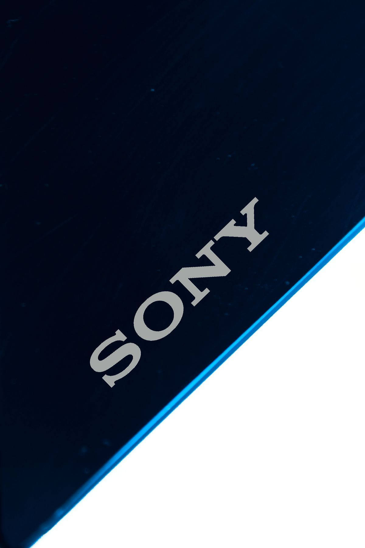Sony 桌布 壁紙 — 特寫一個時尚的深藍色Sony設備，帶有銀色標誌和發光藍色邊緣，背景為白色。