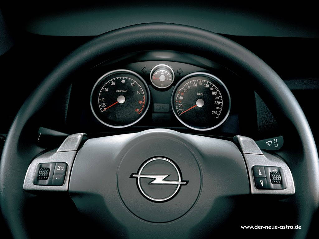 Opel 桌布 壁紙 — 特寫一個時尚的黑色歐寶汽車方向盤，帶有銀色裝飾和昏暗燈光下的發光儀表。
