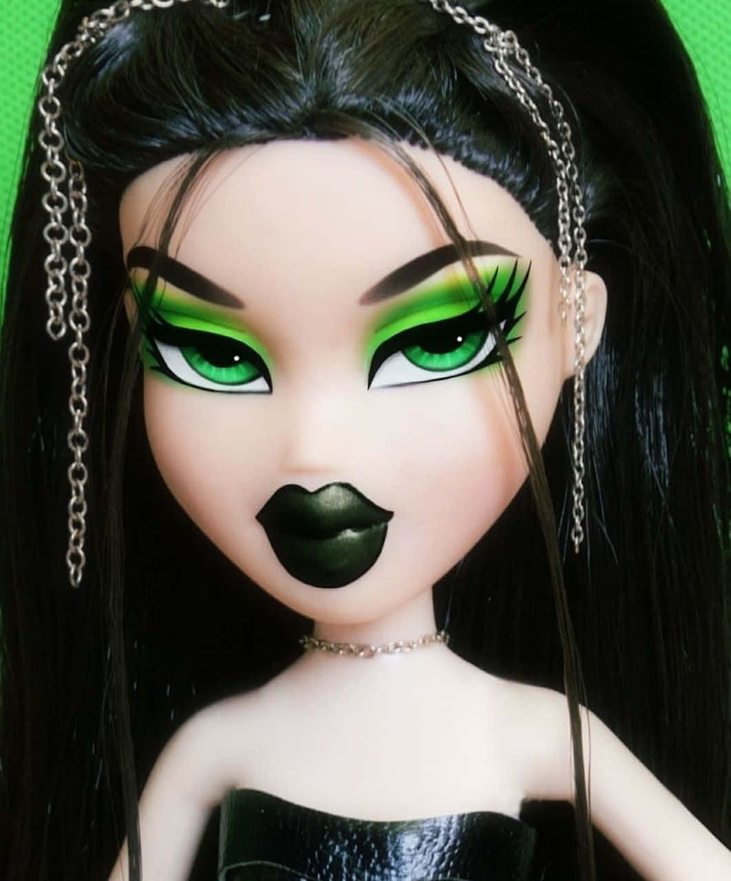 Bratz 桌布 壁紙 — 特寫一個洋娃娃，擁有引人注目的綠色眼睛、大膽的黑色嘴唇和銀色鏈條髮飾，背景是充滿活力的綠色。