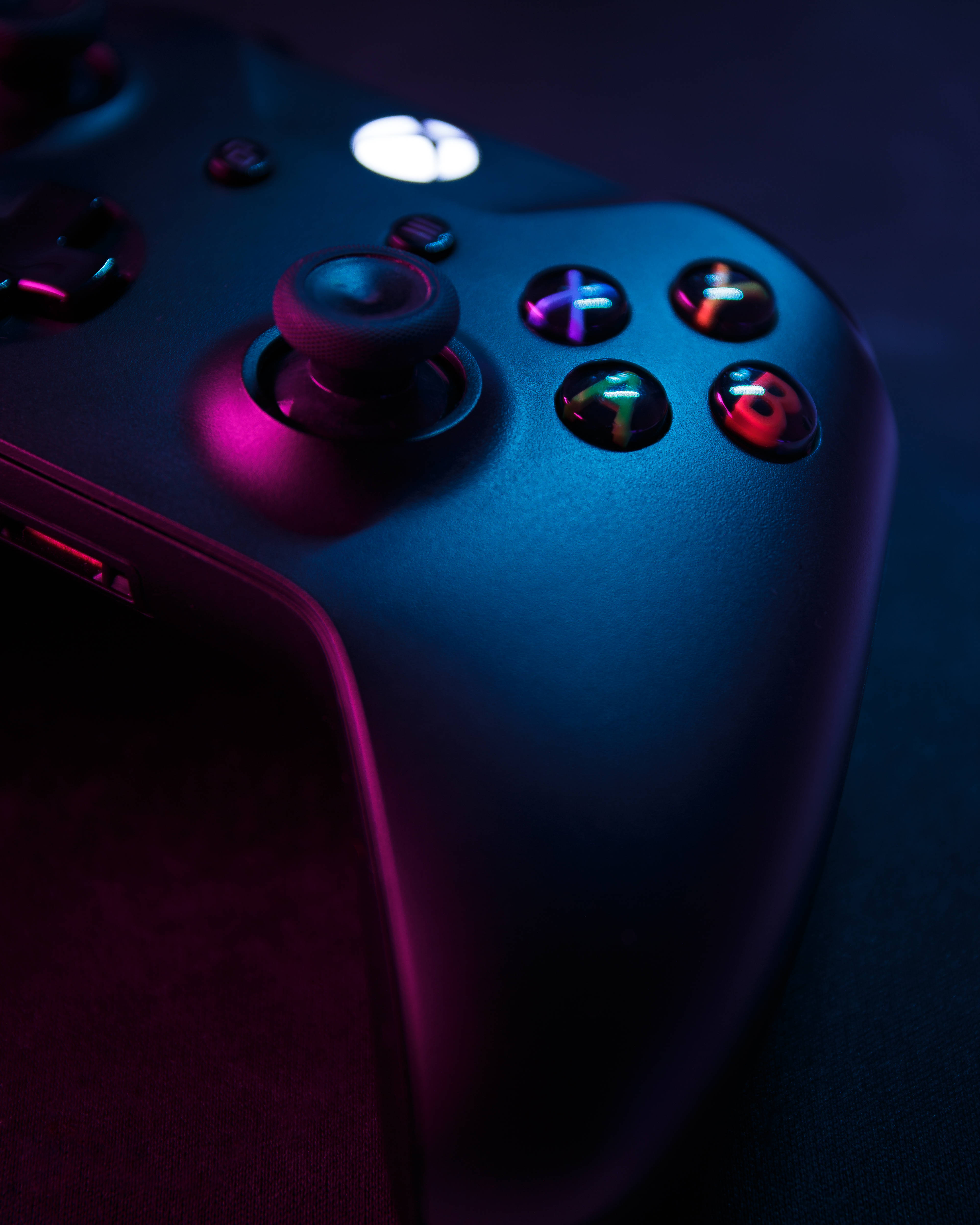 電玩遊戲 桌布 壁紙 — 特寫一個發光的Xbox控制器，在深色背景下沐浴在霓虹藍和粉紅光中。