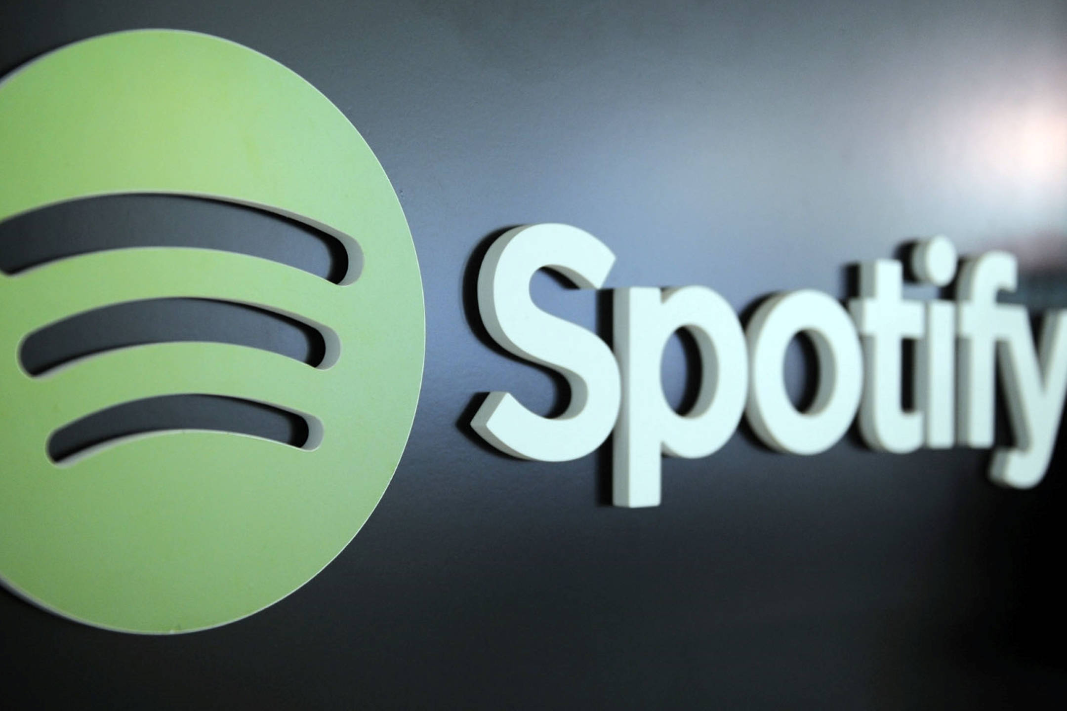 Spotify 桌布 壁紙 — 特寫一個立體Spotify標誌，綠色圓圈和白色文字安裝在深色牆上。