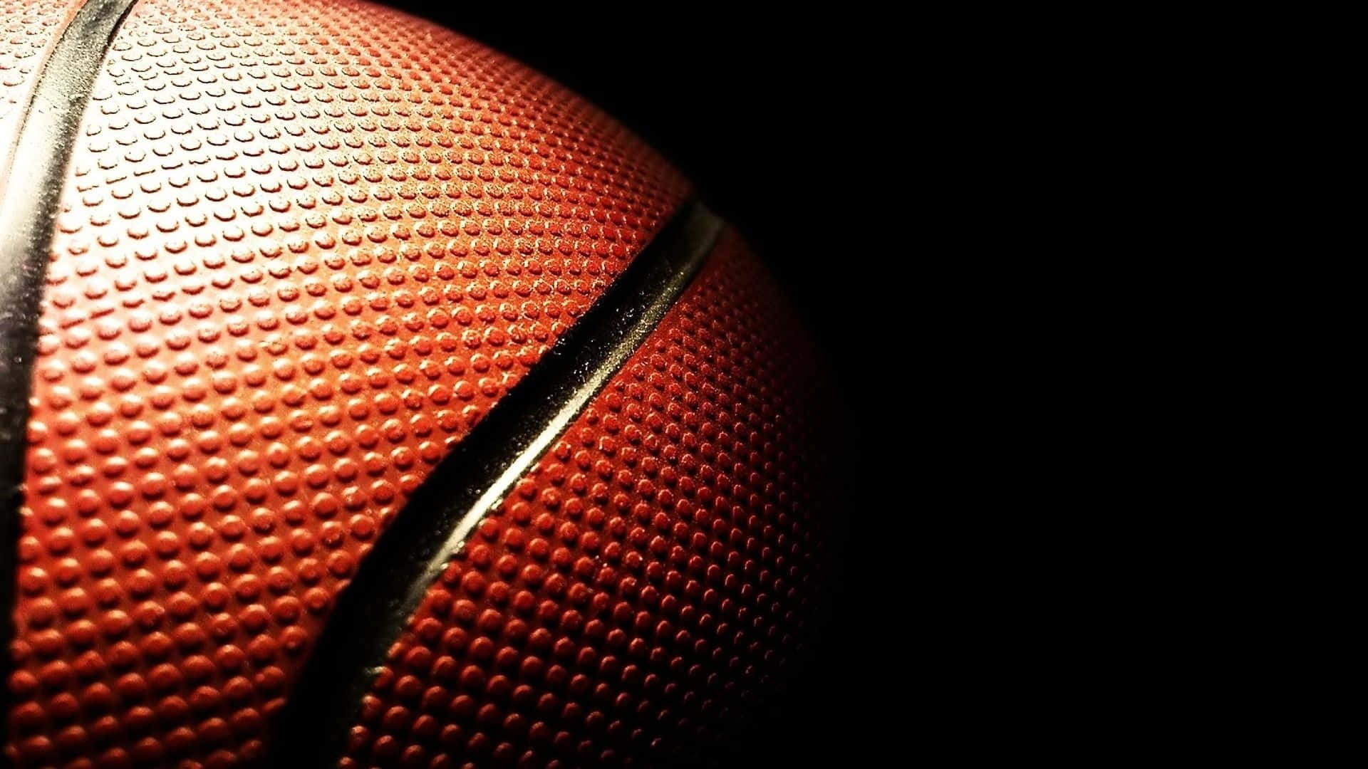 1080p Basketball 桌布 壁紙 — 特寫一個紋理橙色籃球，帶有黑色縫線，背景為純黑色。