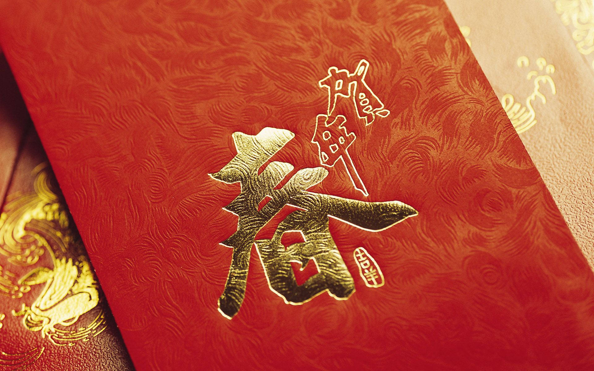 New 桌布 壁紙 — 特寫一個豐富的紅色信封，帶有浮雕金色中文字，用於春節慶祝。