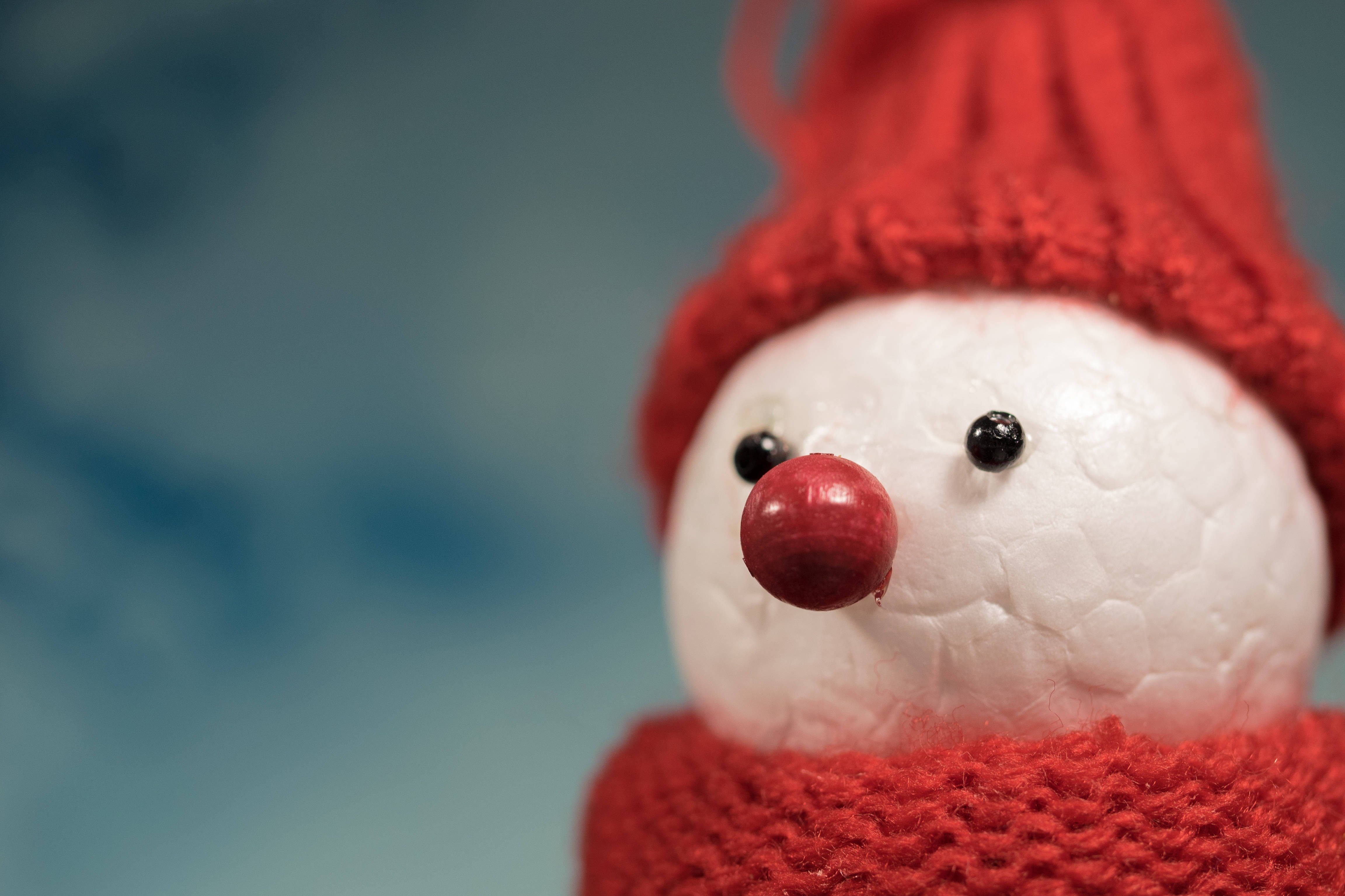 雪人 桌布 壁紙 — 特寫一個迷人的雪人公仔，戴著紅色針織帽和圍巾，背景是柔和的藍色。