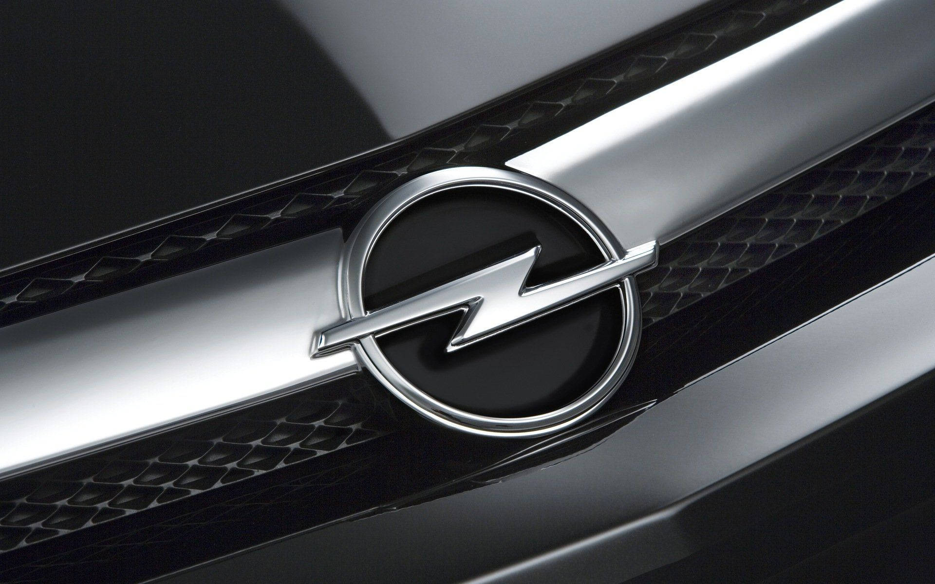 Opel 桌布 壁紙 — 特寫一個閃亮的鍍鉻歐寶標誌，位於黑色紋理汽車格柵中央，帶有銀色飾邊。