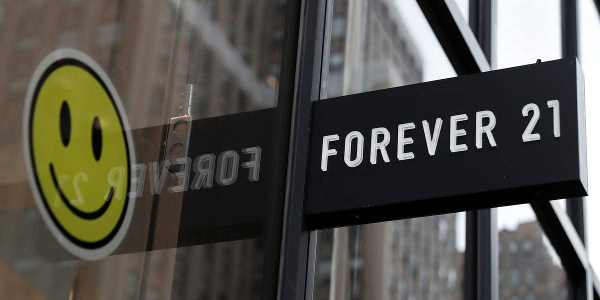 永遠21 桌布 壁紙 — 特寫一個黑色 Forever 21 商店招牌，上面有白色字體，安裝在玻璃店面，上面有一個黃色笑臉貼紙。