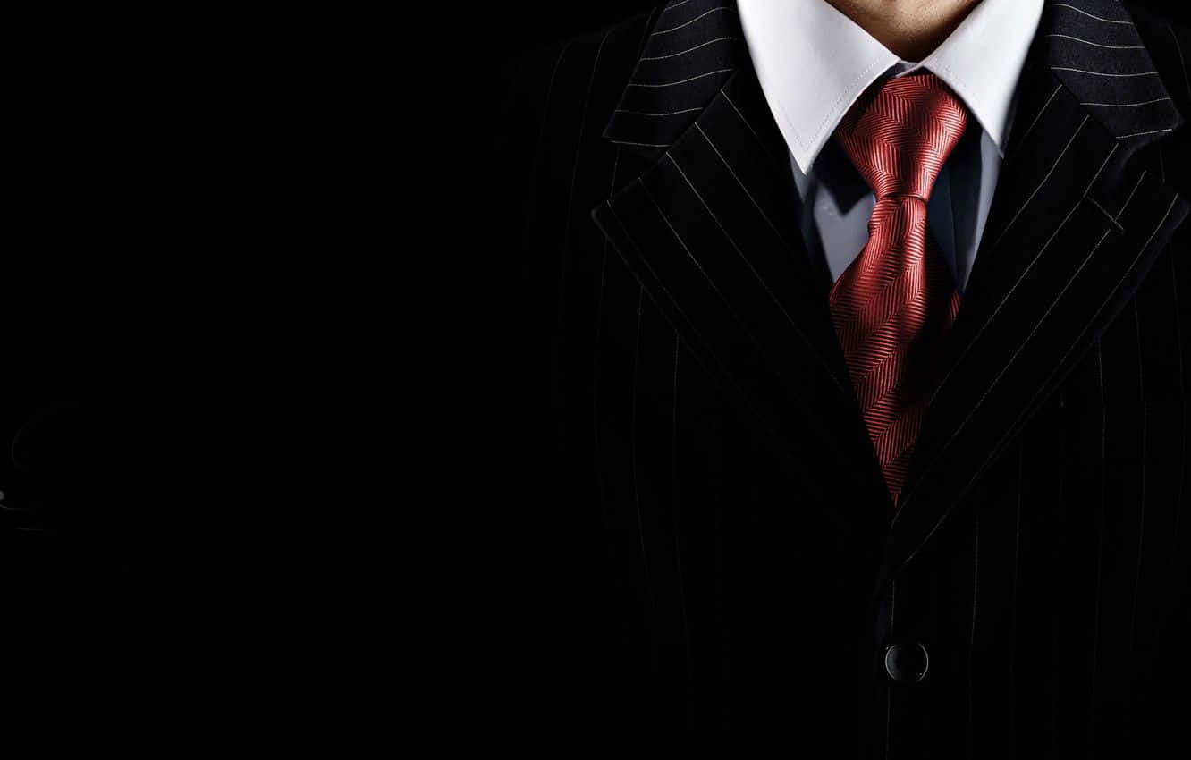 Red Tie 桌布 壁紙 — 特寫一名身穿黑色細條紋西裝、配紅色圖案領帶的男子，背景為深色。