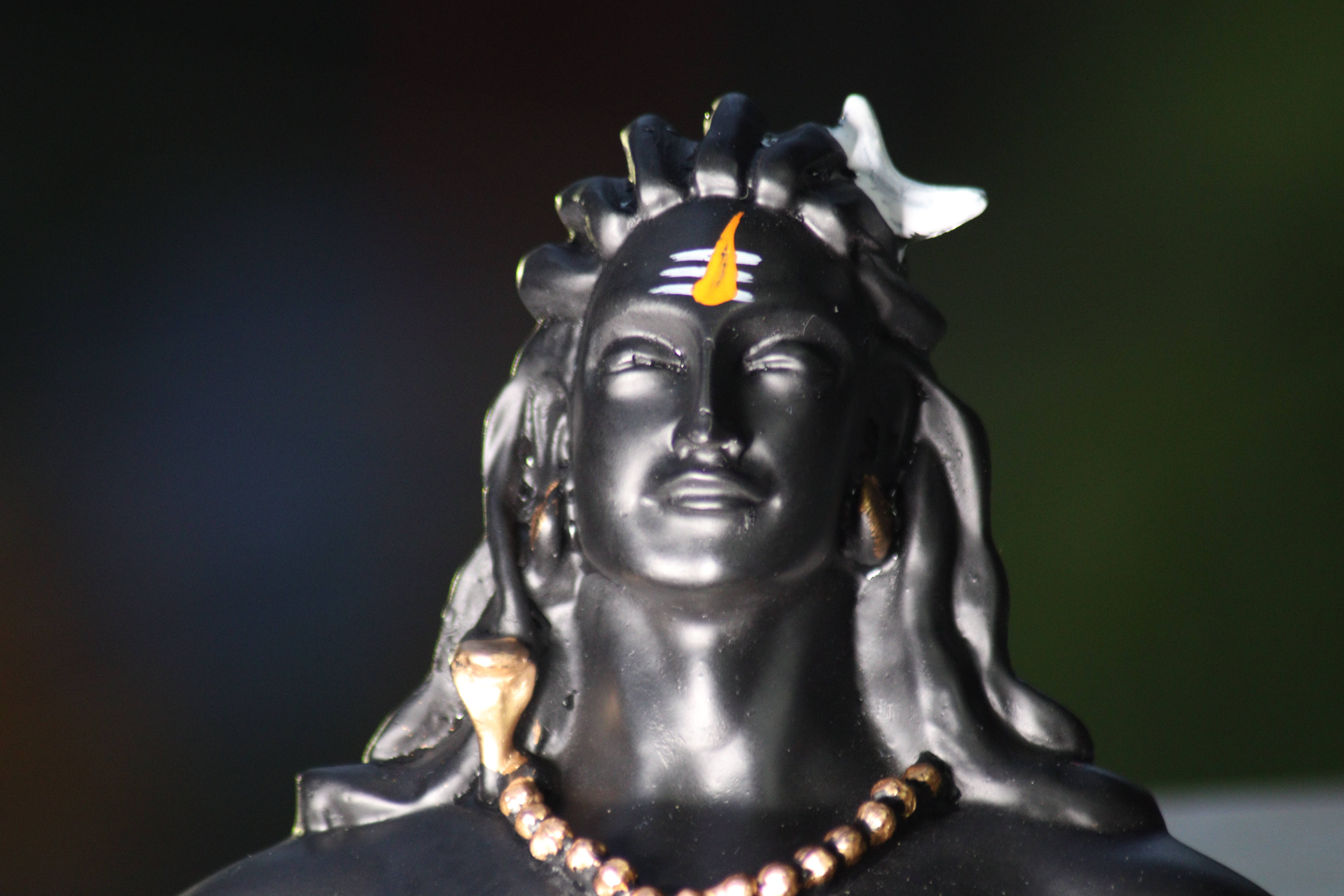 shiv shankar 桌布 壁紙 — 特寫一尊光滑的黑色濕婆神像，閉著眼睛，飾有黃色提拉克和白色新月冠。