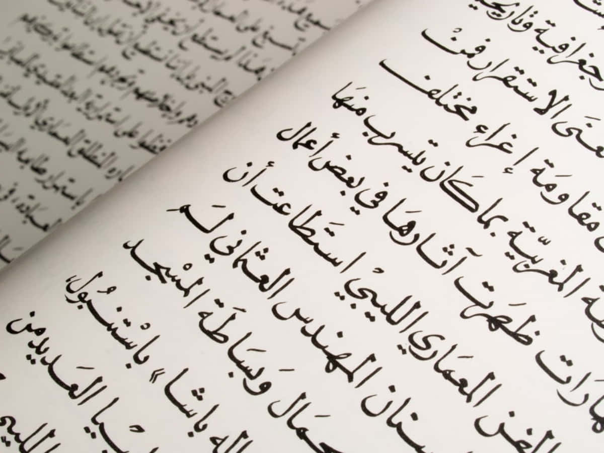 arabic 桌布 壁紙 — 特寫一本打開的書，奶油色紙張上有優雅的黑色阿拉伯書法，對角傾斜。
