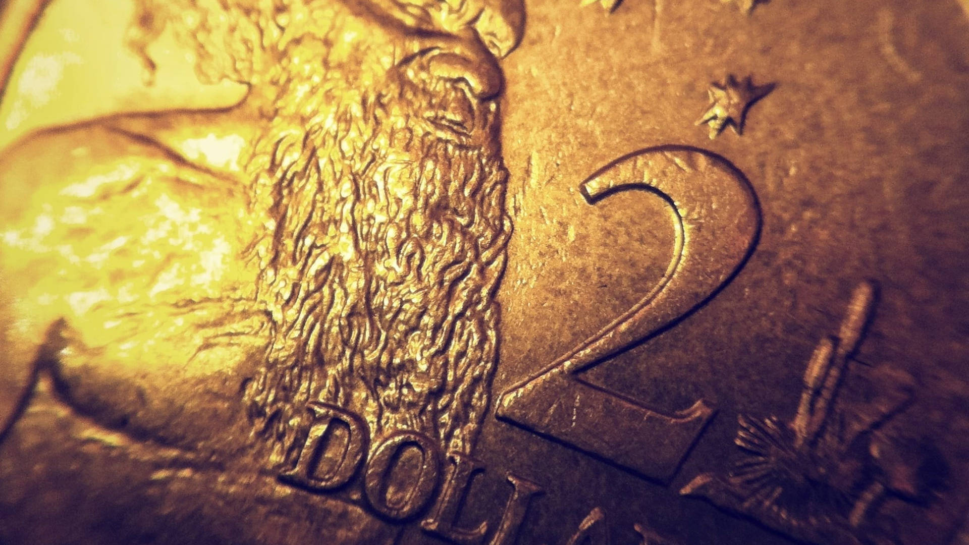 金錢 桌布 壁紙 — 特寫一枚金色兩美元硬幣，在溫暖燈光下顯示細緻的鬍鬚紋理和浮雕數字。