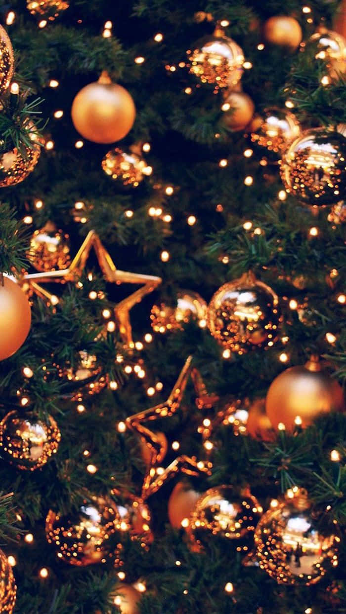 Aesthetic Christmas Tree 桌布 壁紙 — 特寫一棵茂盛的綠色聖誕樹，裝飾著閃閃發光的金色飾物和閃爍的仙女燈。