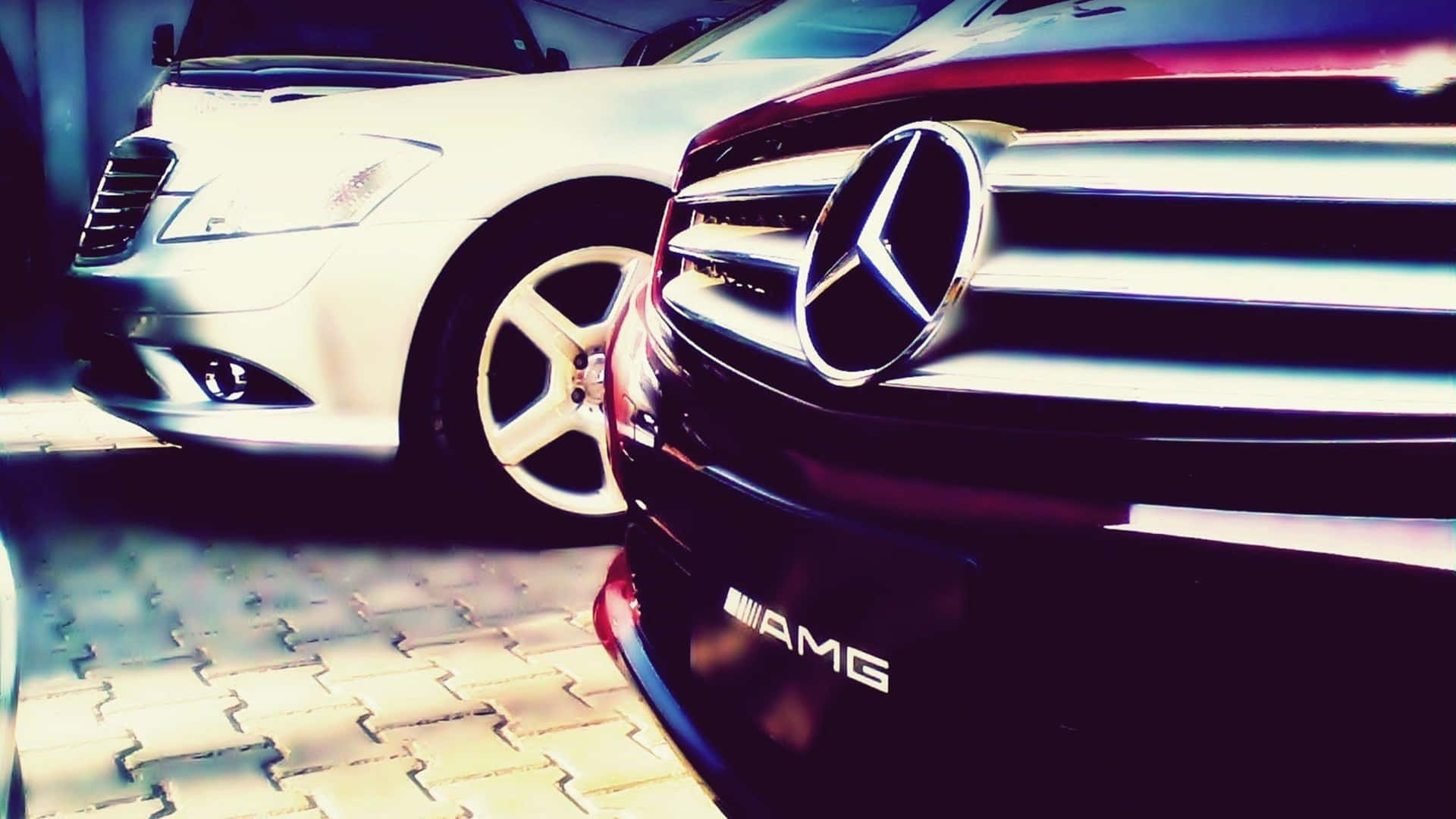 Mercedes 桌布 壁紙 — 特寫一輛亮紅色 Mercedes-AMG 和白色轎車停放在圖案路面上的明亮光線下。
