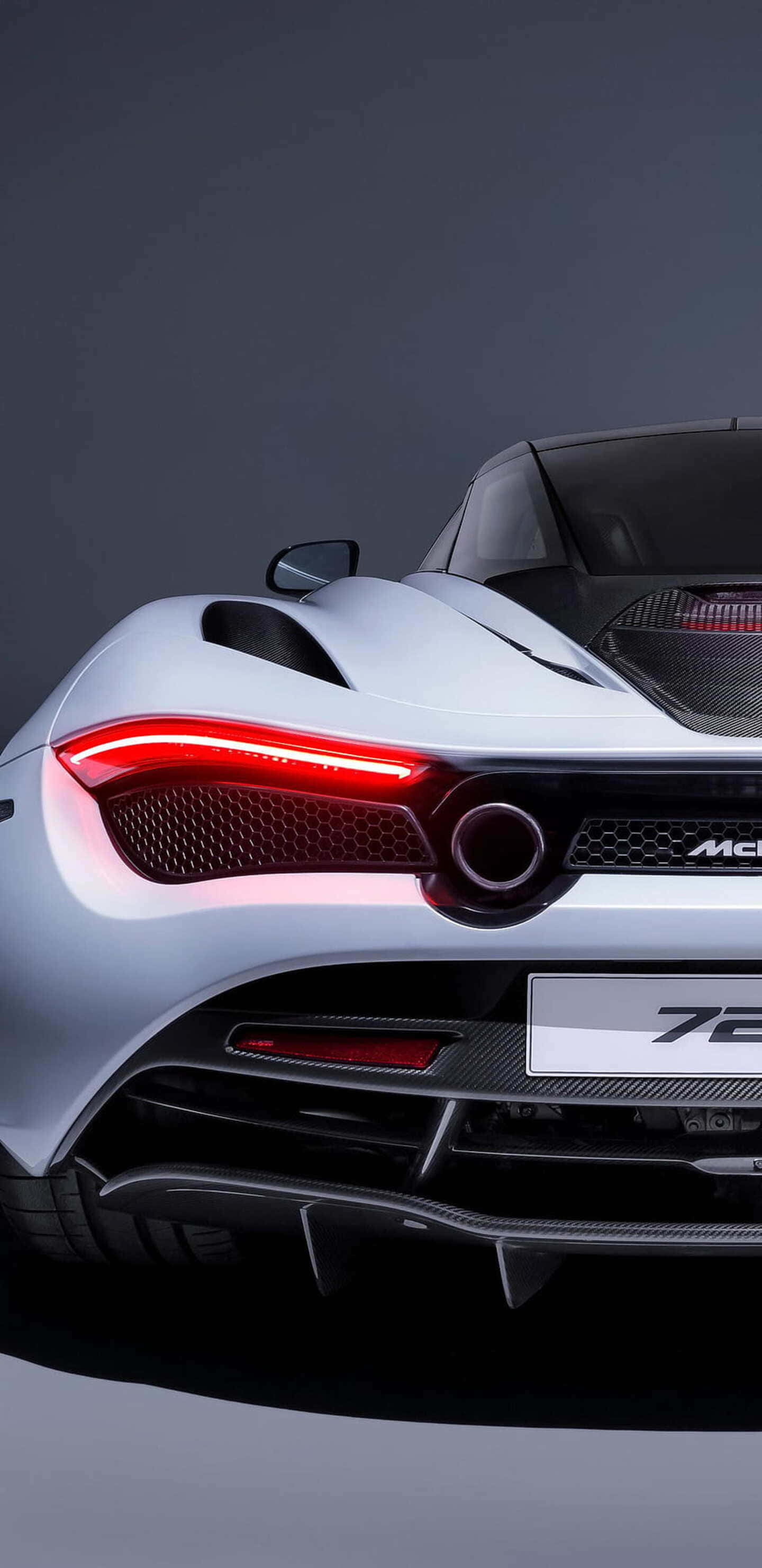 Pixel 3xl Mclaren 720s 桌布 壁紙 — 特寫一輛銀色McLaren 720S跑車在黑暗工作室背景下的發光紅色尾燈。