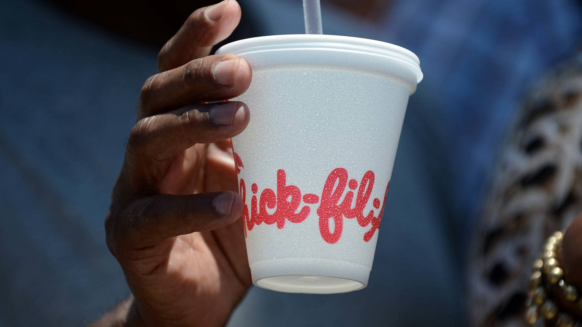 chick 桌布 壁紙 — 特寫一隻手拿著帶有吸管的Chick-fil-A泡沫杯，背景模糊。