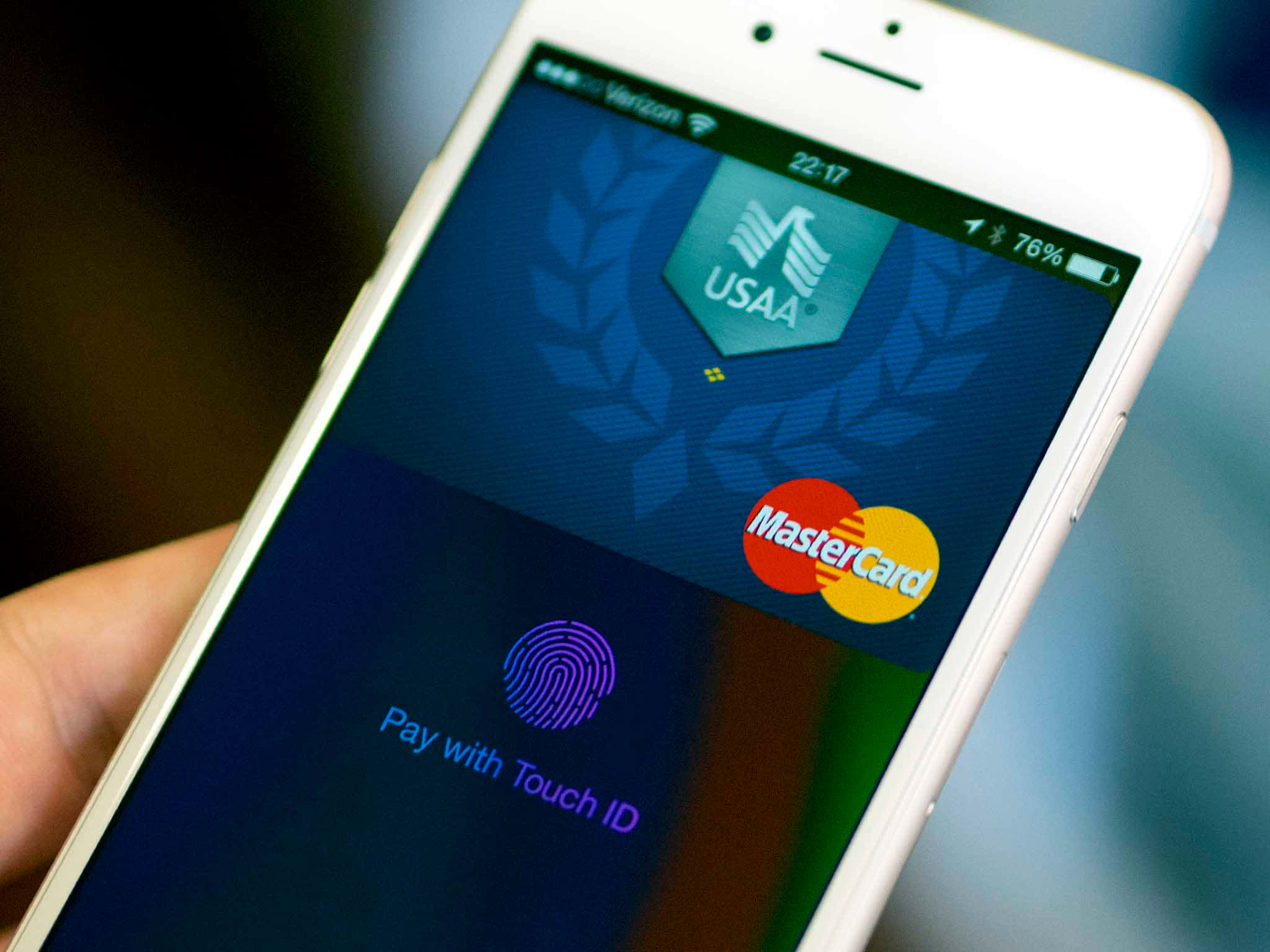 Smartphone 桌布 壁紙 — 特寫一隻手拿著白色iPhone，顯示USAA MasterCard付款畫面及Touch ID提示。