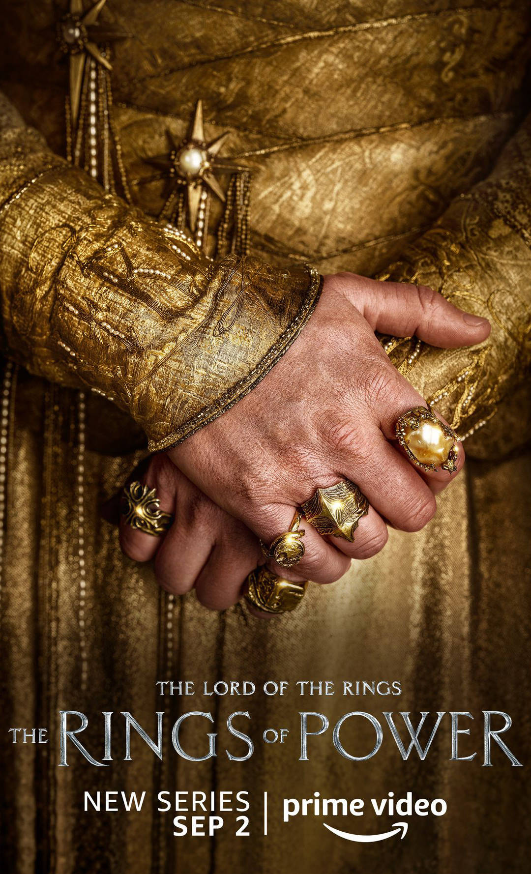 Lotr 桌布 壁紙 — 特寫一隻飽經風霜的手緊握另一隻手，兩隻手都戴著華麗的金戒指，背景是質感豐富的金色布料。