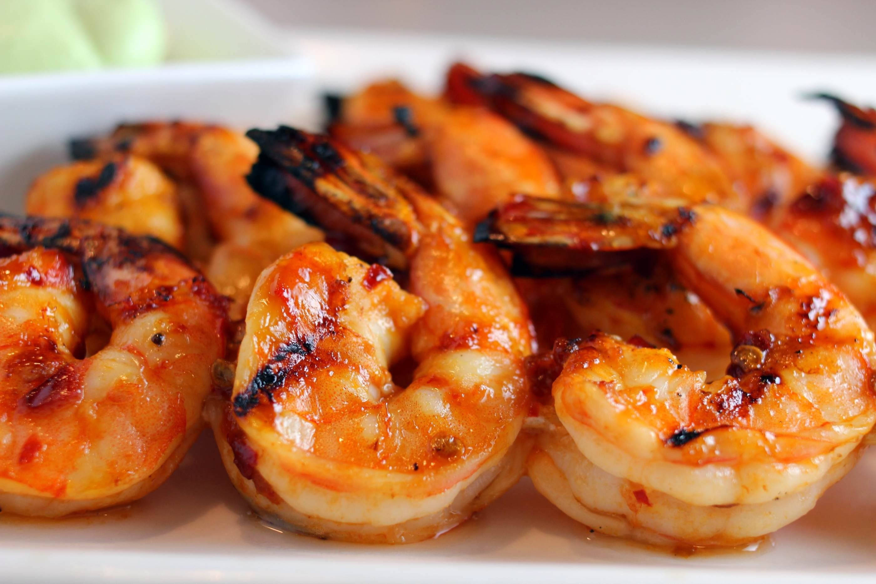 Prawns 桌布 壁紙 — 特寫多汁烤蝦，帶有焦糖釉光澤，放在白色盤子上。