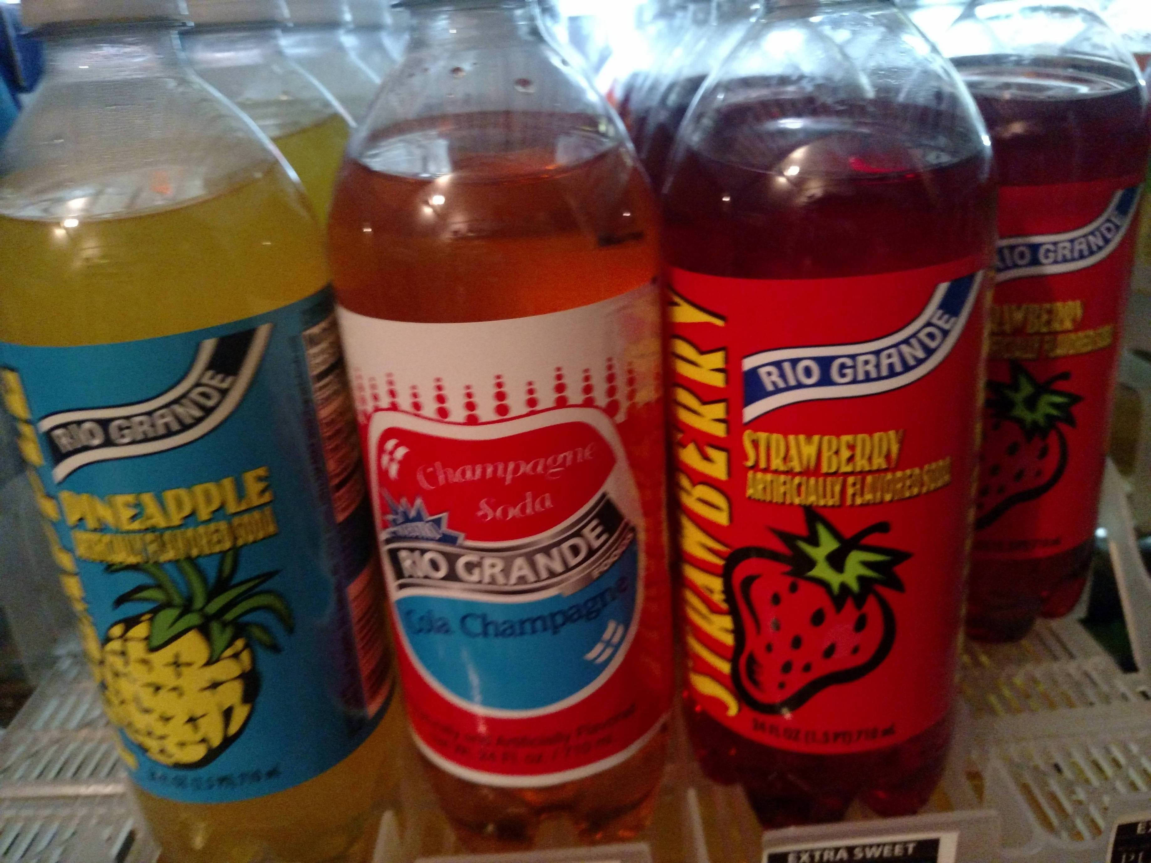 Drink 桌布 壁紙 — 特寫展示鳳梨香檳和草莓口味的冷藏陳列櫃中色彩繽紛的Rio Grande汽水瓶。