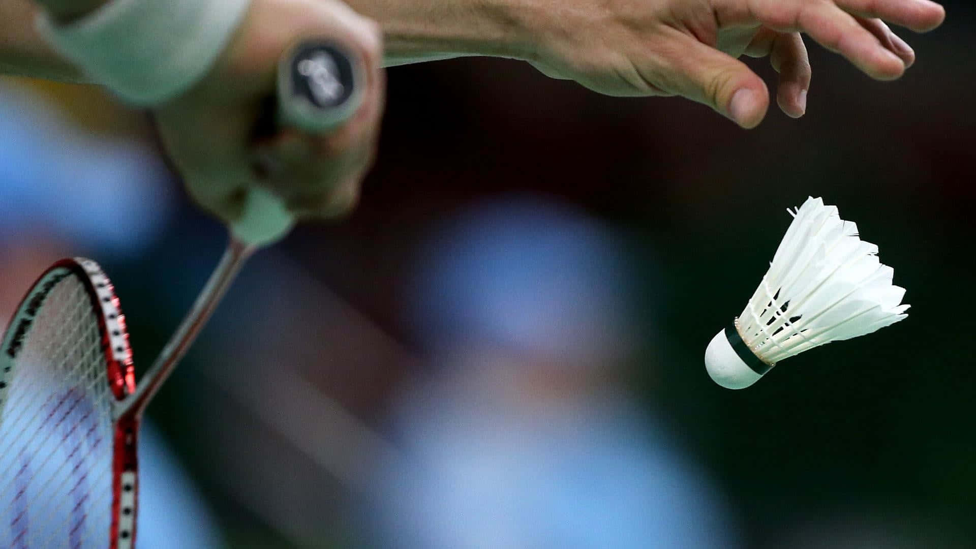 HD Badminton 桌布 壁紙 — 特寫捕捉到羽毛球選手的手緊握球拍，白色羽毛球在空中飛過。