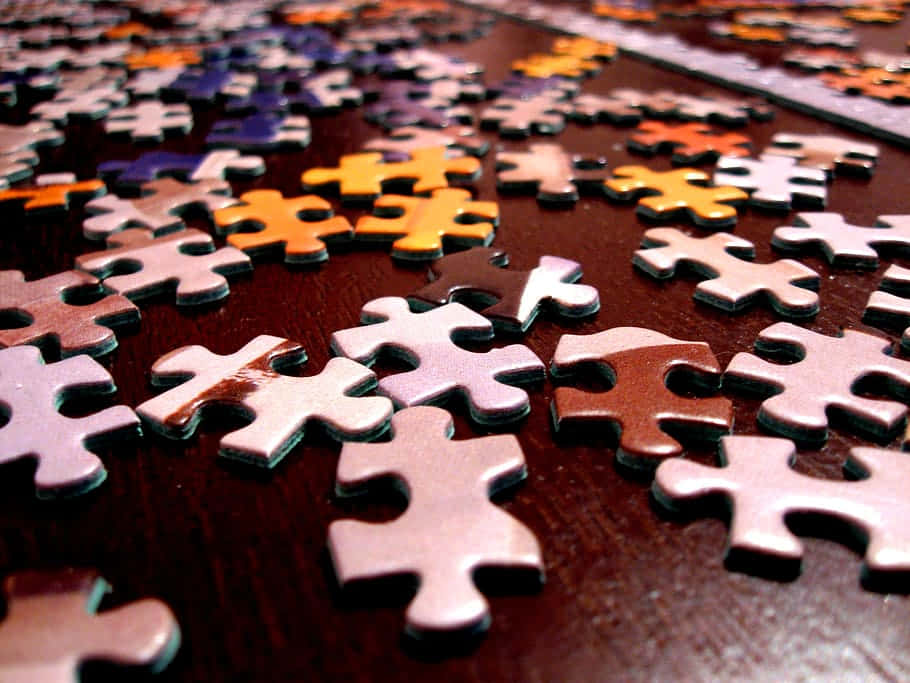 Puzzle Games 桌布 壁紙 — 特寫散落的拼圖碎片在深色木質表面上，帶有溫暖的燈光。