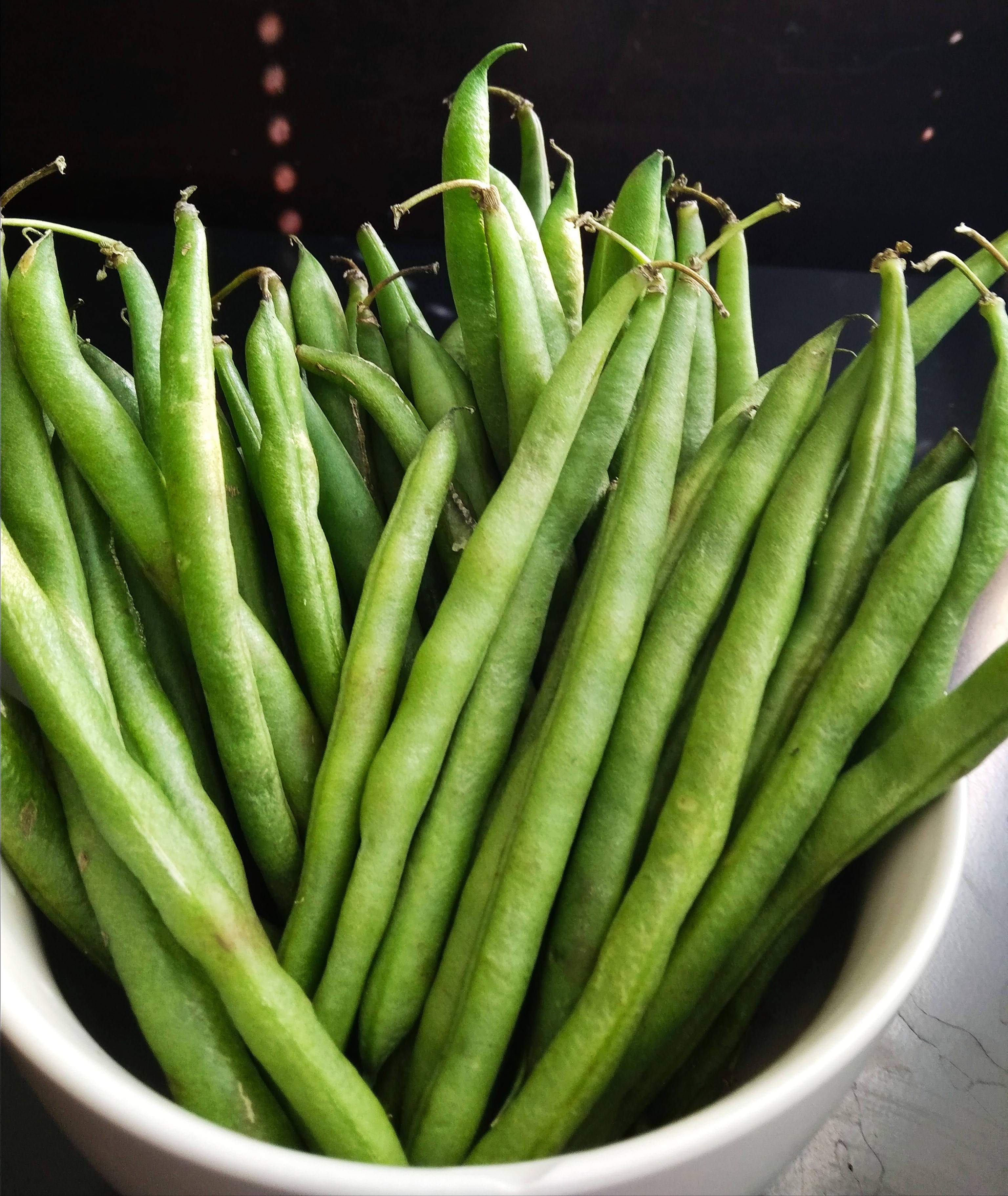 beans 桌布 壁紙 — 特寫新鮮翠綠的豆角高高堆在白色陶瓷碗中，背景深色。