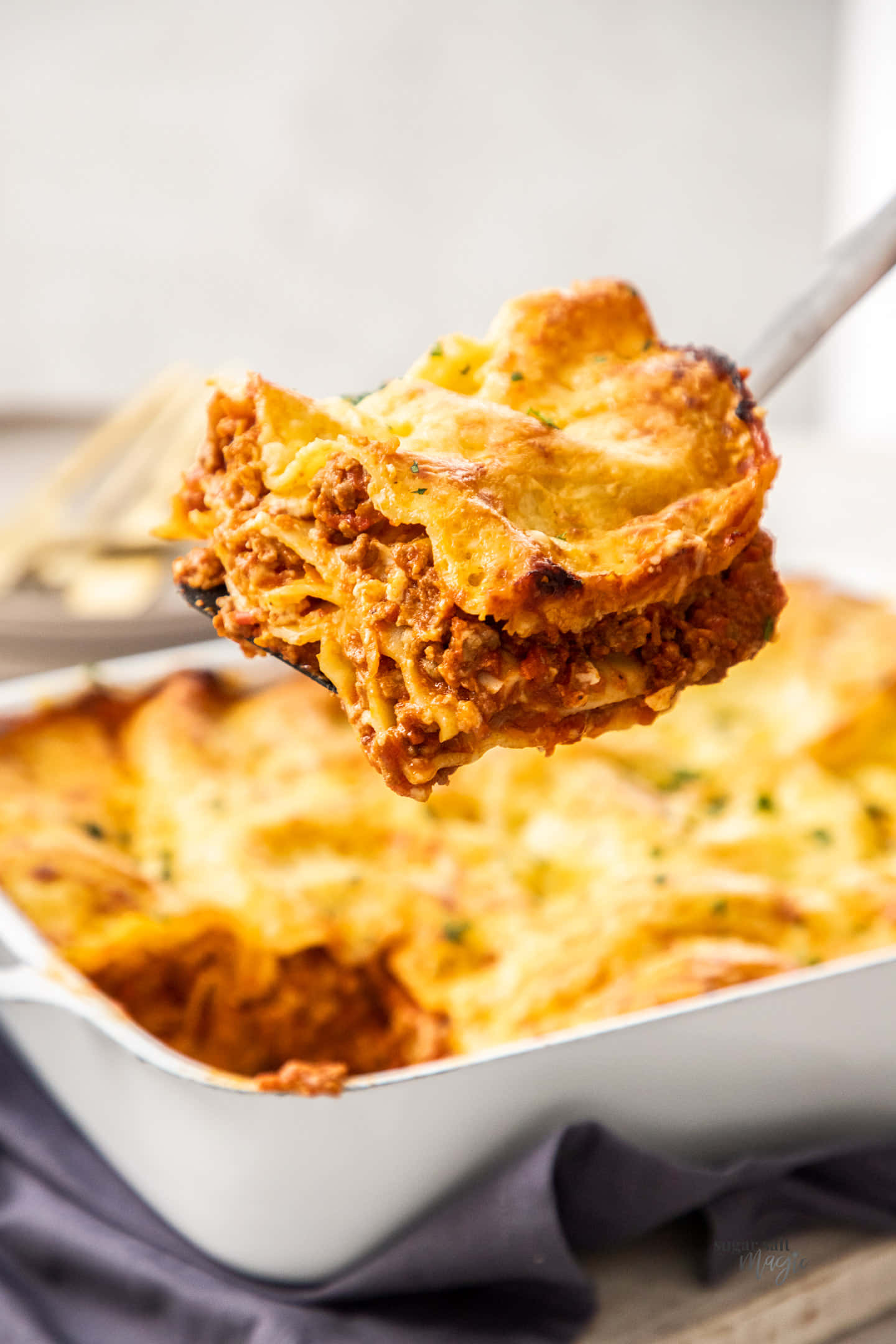 Food Photography 桌布 壁紙 — 特寫照片，湯匙從白色烤盤中舀起一層金黃色起司千層麵。