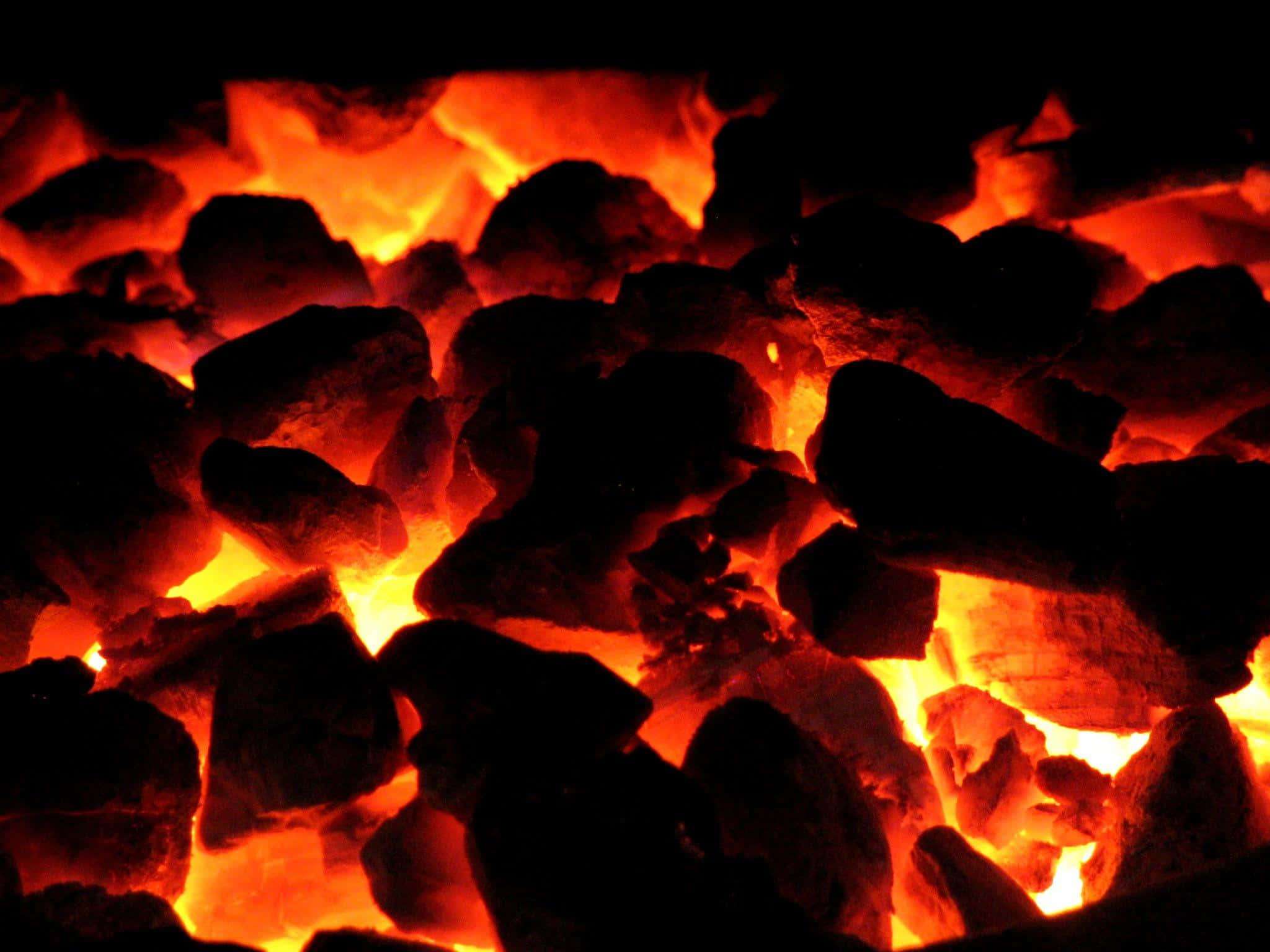 Charcoal 桌布 壁紙 — 特寫發光餘燼在黑暗背景下散發出強烈的橙色和黃色熱量。