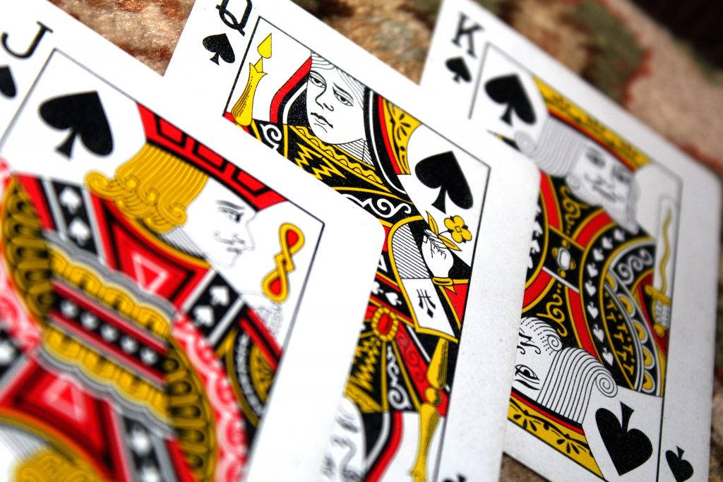 game 桌布 壁紙 — 特寫皇家撲克牌傑克、皇后和國王黑桃以扇形展開在紋理表面上。