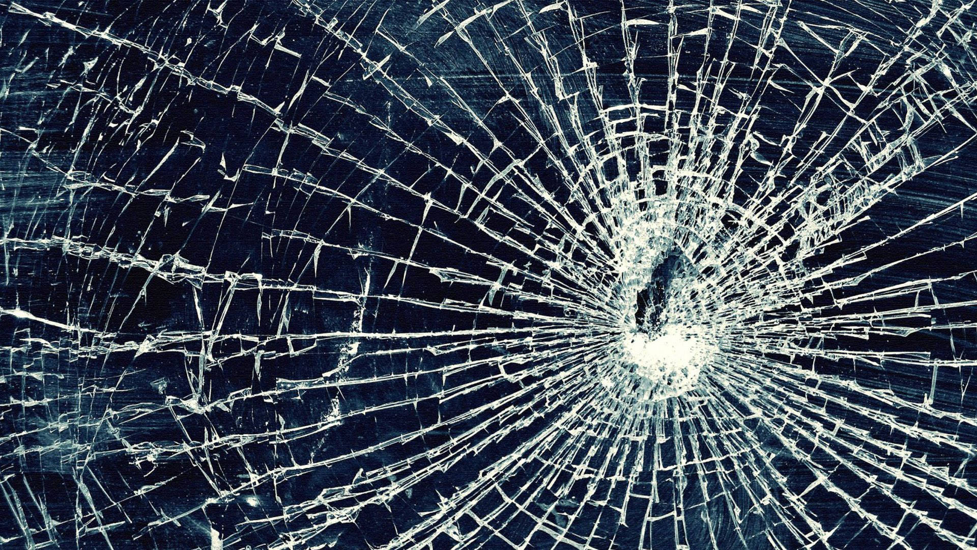 cracked 桌布 壁紙 — 特寫破碎玻璃，中央撞擊點在深藍色背景上放射出裂紋。