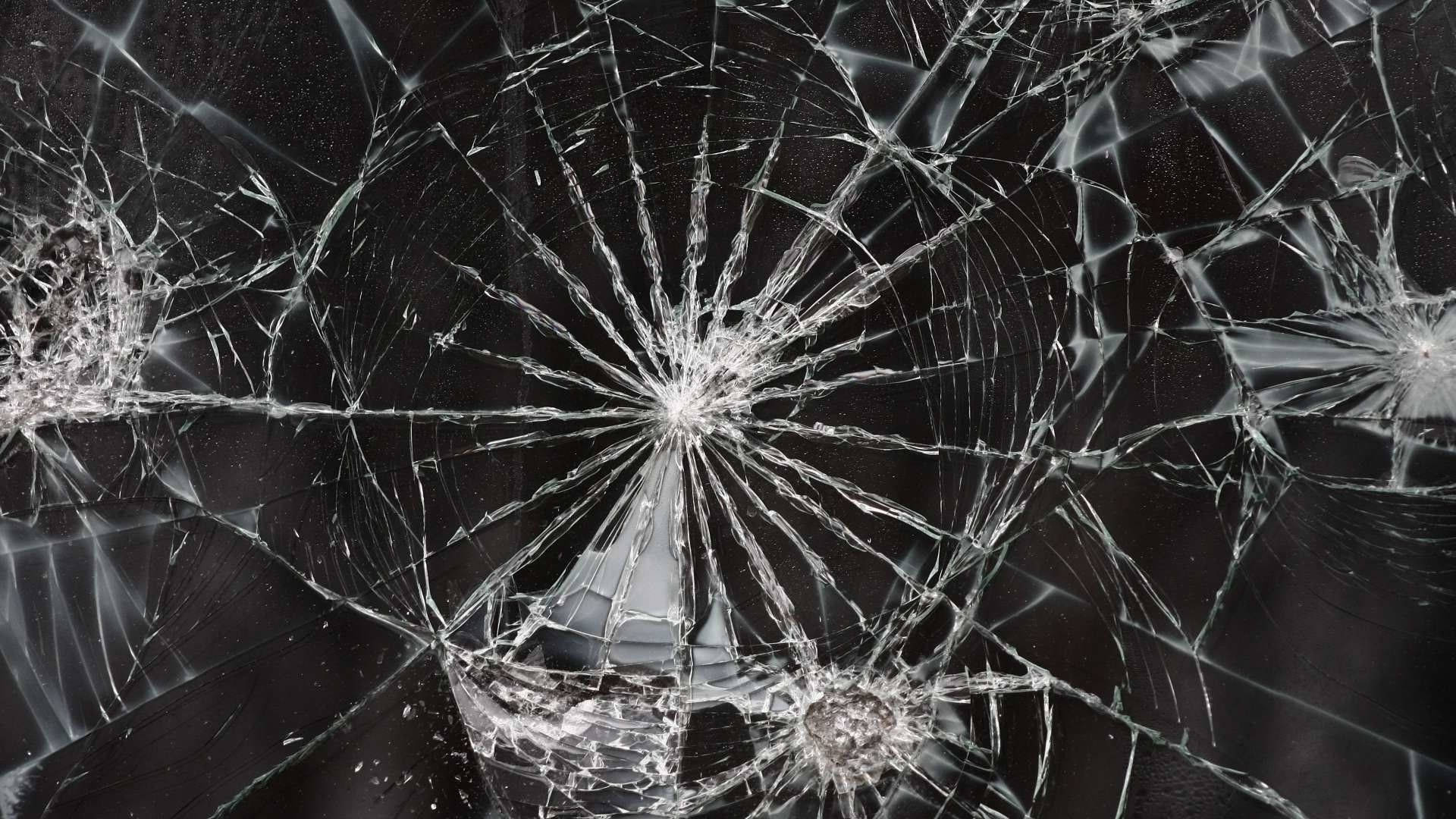 Screen 桌布 壁紙 — 特寫破碎玻璃，裂紋從撞擊點向外擴散，背景深色。