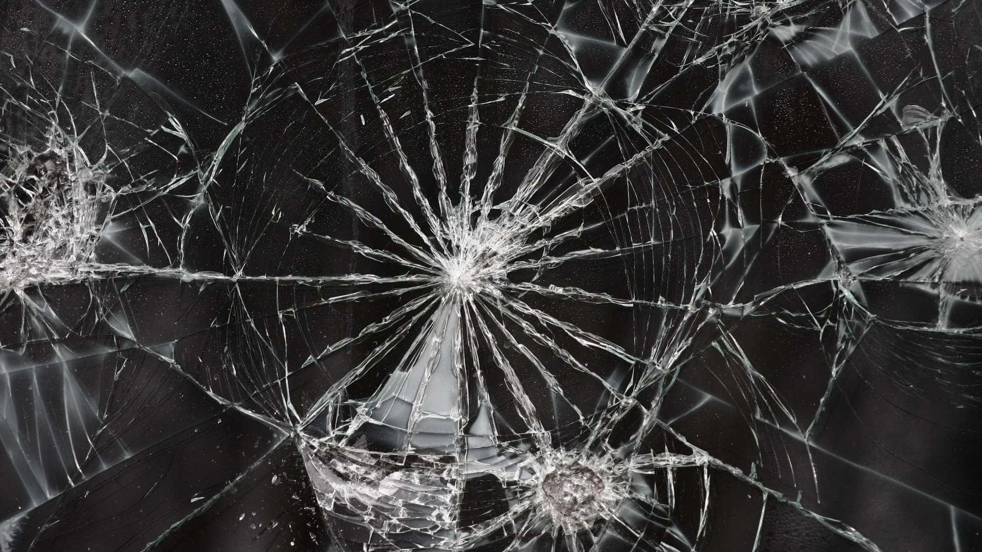 Screensavers 桌布 壁紙 — 特寫破碎玻璃，裂紋從撞擊點向外擴散，背景深色。