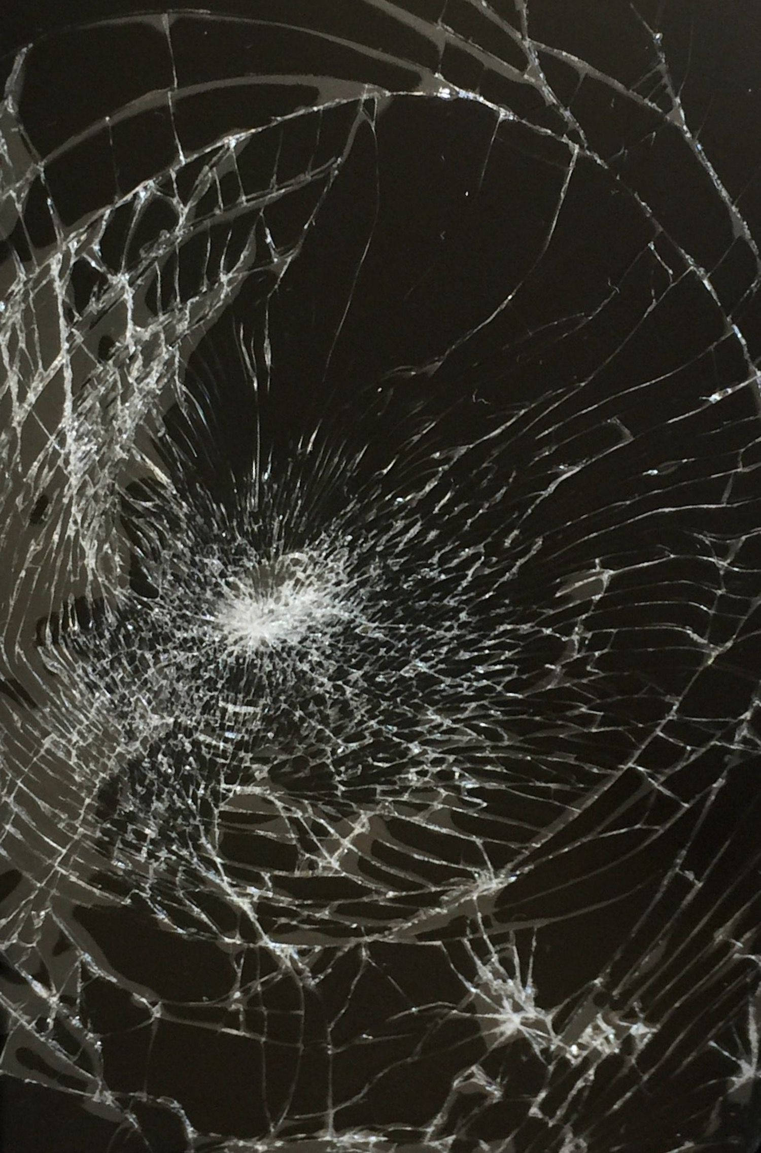 Screen 桌布 壁紙 — 特寫破碎玻璃，複雜裂紋從中央撞擊點向外輻射，背景為深色。