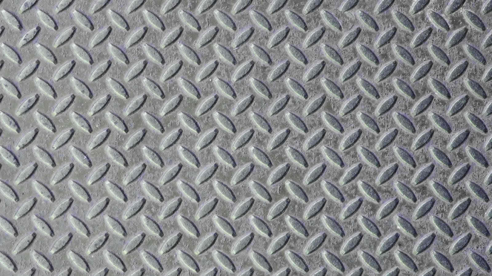 Diamond Plate 桌布 壁紙 — 特寫紋理鑽石板金屬表面，帶有重複的凸起橢圓圖案和微妙的灰色高光。