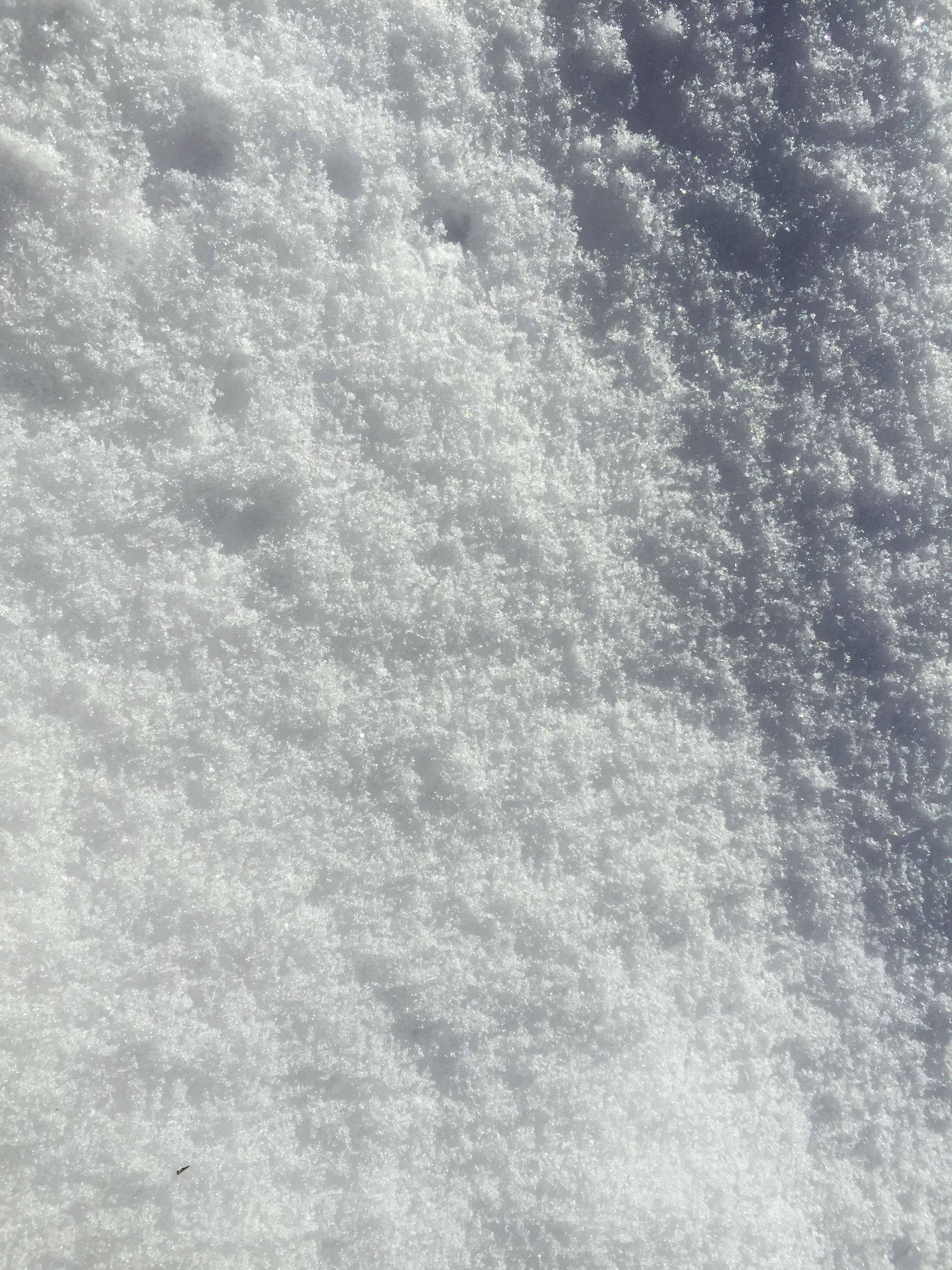 White Texture 桌布 壁紙 — 特寫紋理雪地，陽光照射的晶體和柔和陰影營造寧靜的冬季場景。