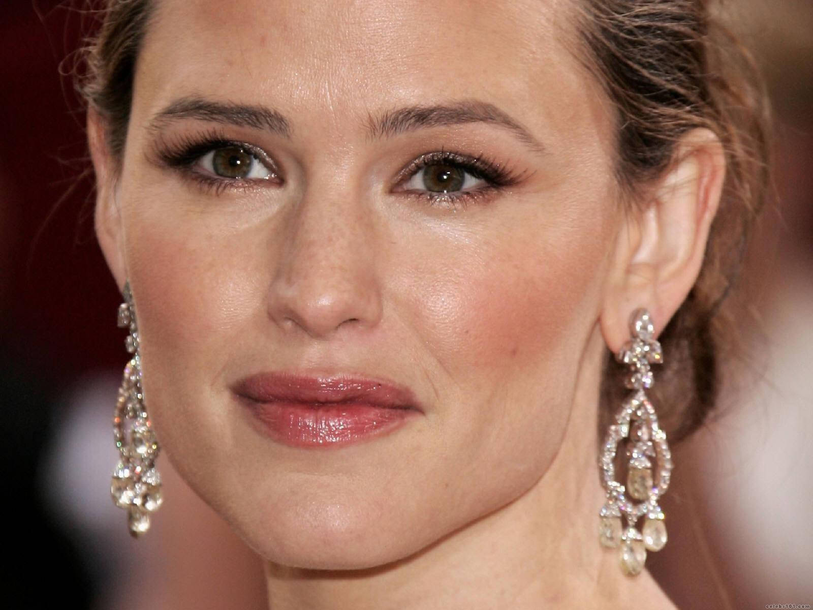 Celebrity 桌布 壁紙 — 特寫肖像，一位女士佩戴優雅的鑽石吊燈耳環，妝容柔和，背景為模糊的紅色。