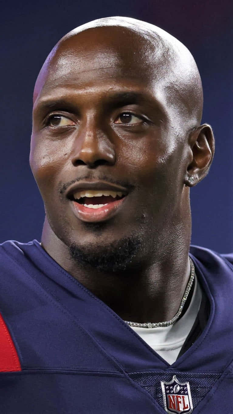 Devin Mccourty 桌布 壁紙 — 特寫肖像，一位微笑的光頭黑人NFL美式足球員穿著紫色球衣，背景為深藍色。