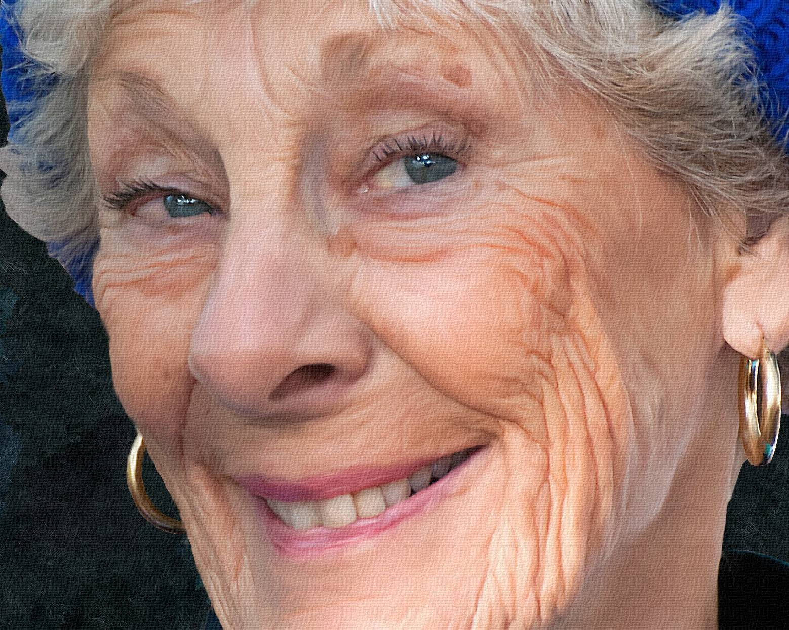 Woman 桌布 壁紙 — 特寫肖像，一位微笑的老年女性，藍色眼睛，戴著金色圓環耳環，背景為深色。