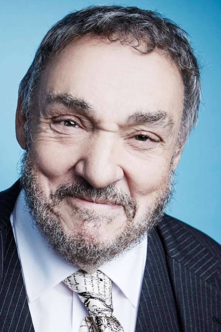 Celebrity 桌布 壁紙 — 特寫肖像，一位微笑的老年男性，灰色鬍鬚，穿著細條紋西裝，背景為純藍色。