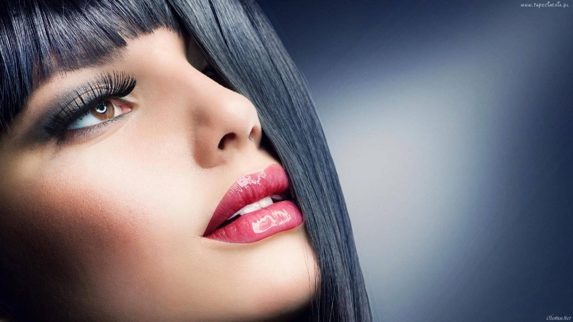 彩妝 桌布 壁紙 — 特寫肖像，一位擁有光澤紅唇和深色頭髮的女性在柔和模糊的背景前向上凝視。