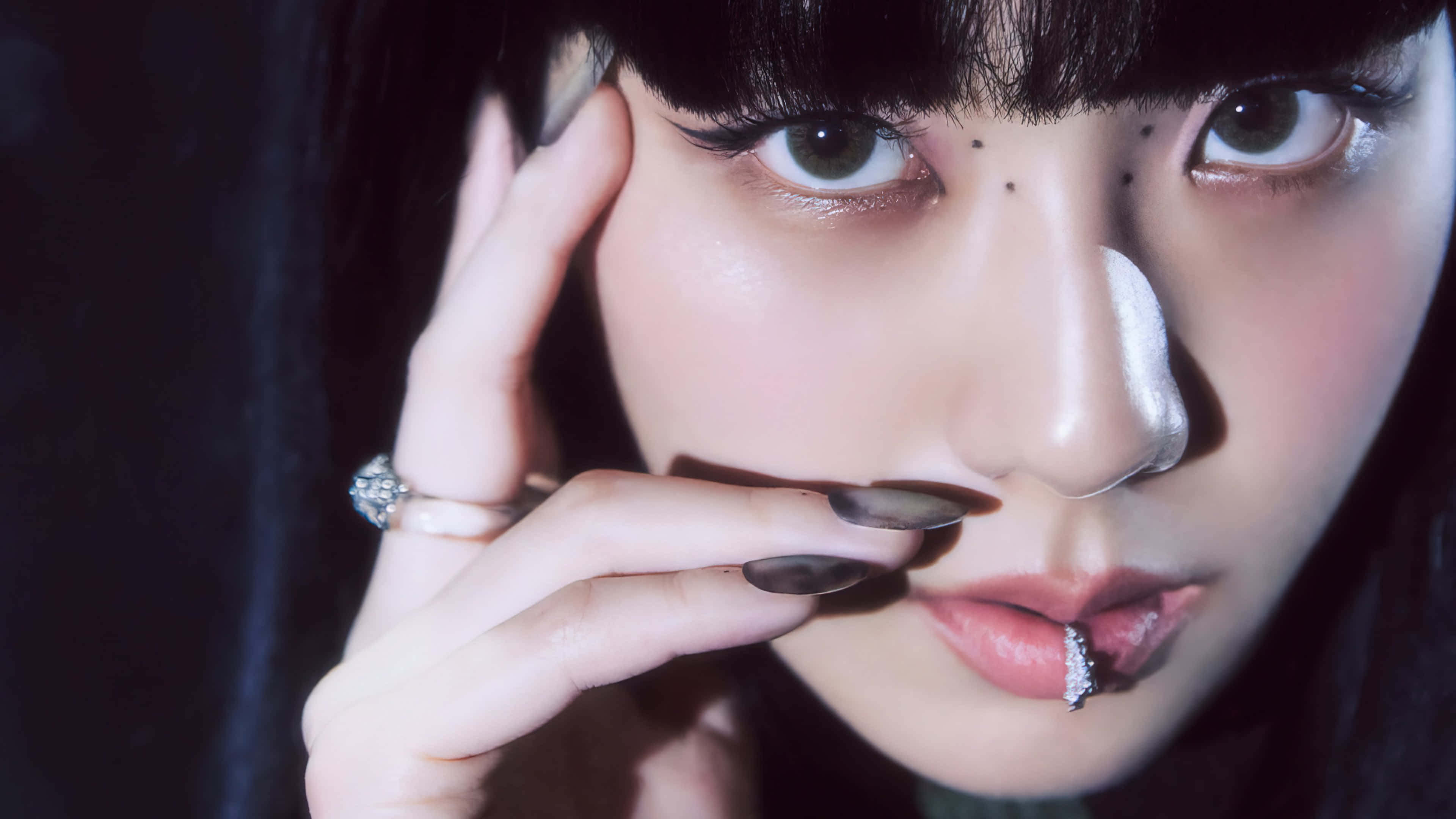 BLACKPINK 桌布 壁紙 — 特寫肖像，一位深色頭髮、妝容誇張的女性在昏暗燈光下將香煙靠近嘴唇。