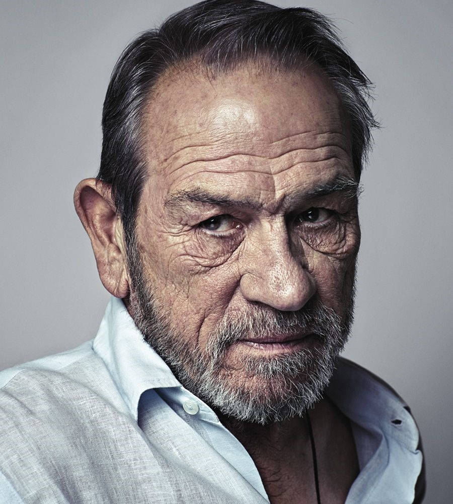 Celebrity 桌布 壁紙 — 特寫肖像，一位飽經風霜的老年男性，有深深的皺紋和灰色鬍鬚，背景為純灰色。