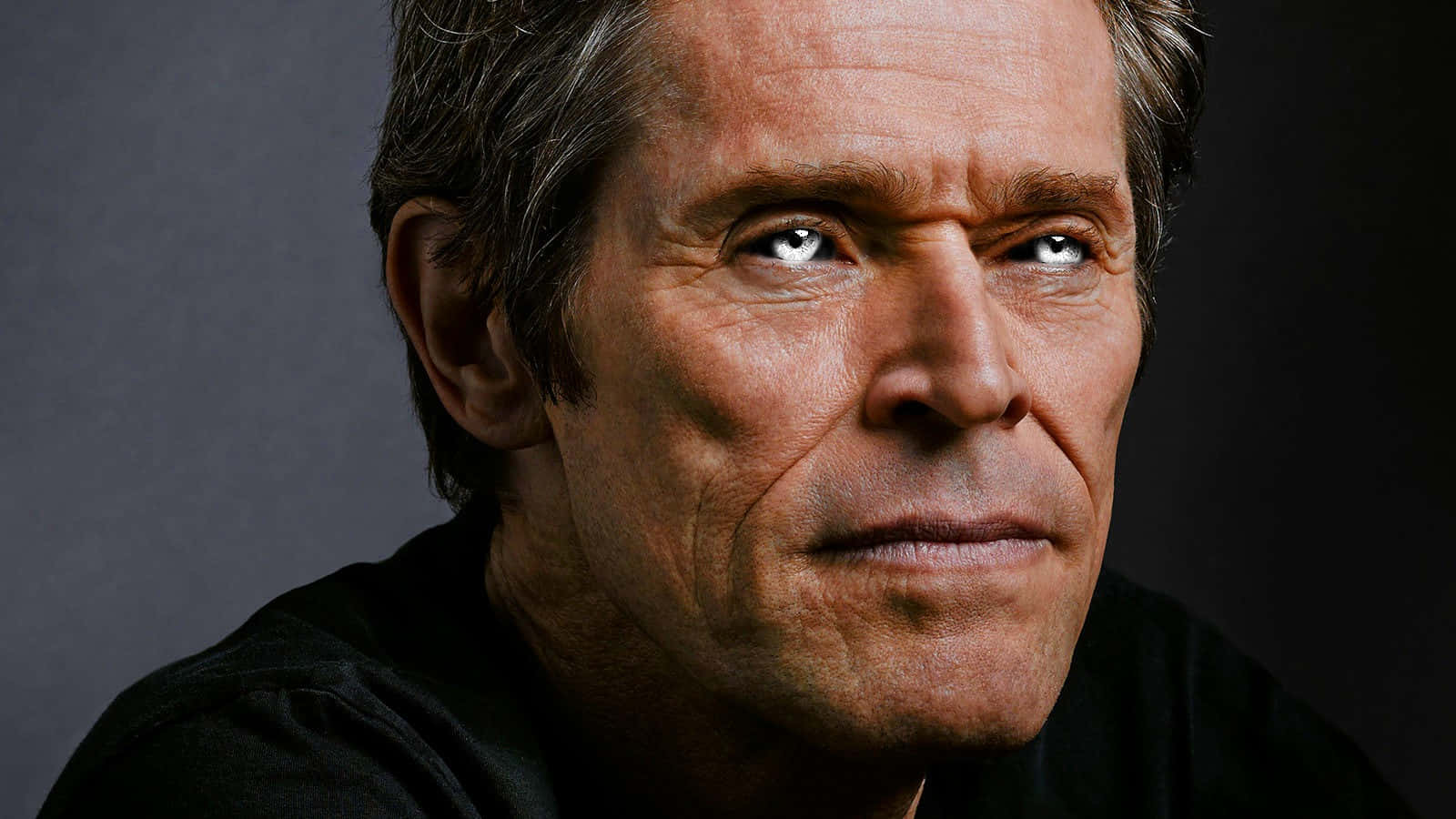 Norman Osborn 桌布 壁紙 — 特寫肖像，一個飽經風霜的男人，擁有強烈的藍色眼睛和灰色頭髮，背景為深灰色。