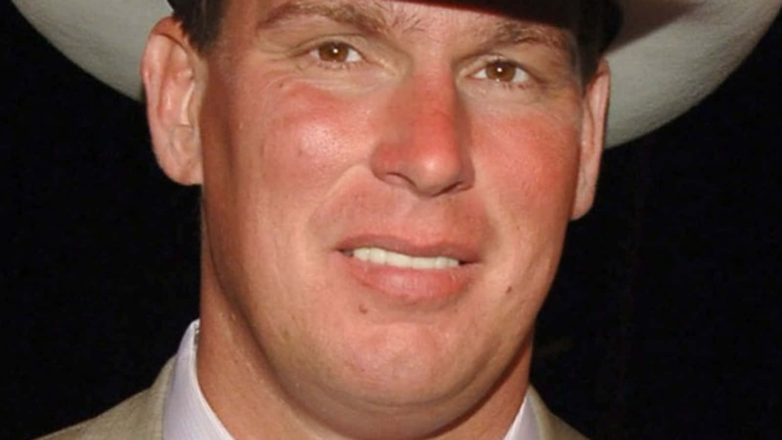 WWE 桌布 壁紙 — 特寫肖像，一名微笑男子戴著白色牛仔帽，背景為深色。