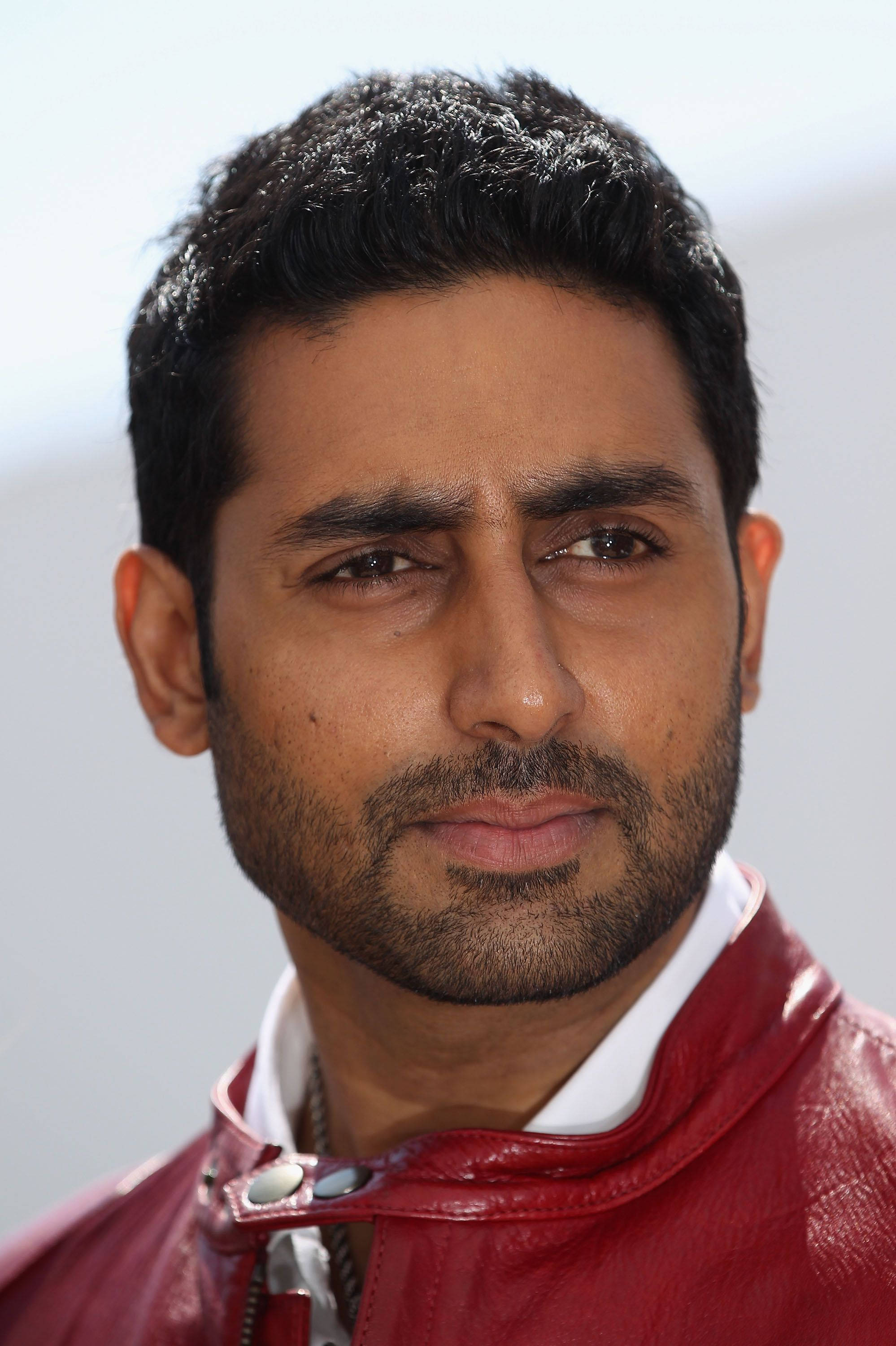 abhishek bachchan 桌布 壁紙 — 特寫肖像，一名深色頭髮和鬍鬚的男子穿著紅色皮夾克，背景為柔和的白色。