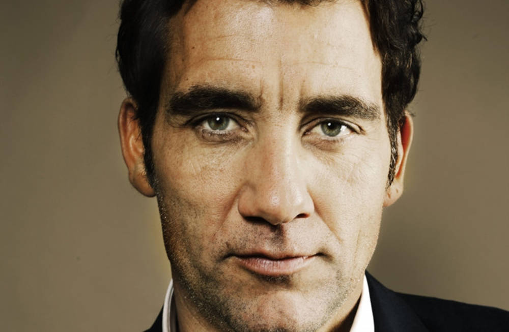 Celebrity 桌布 壁紙 — 特寫肖像，一名男子擁有強烈的綠色眼睛和深色頭髮，背景為柔和的棕色。
