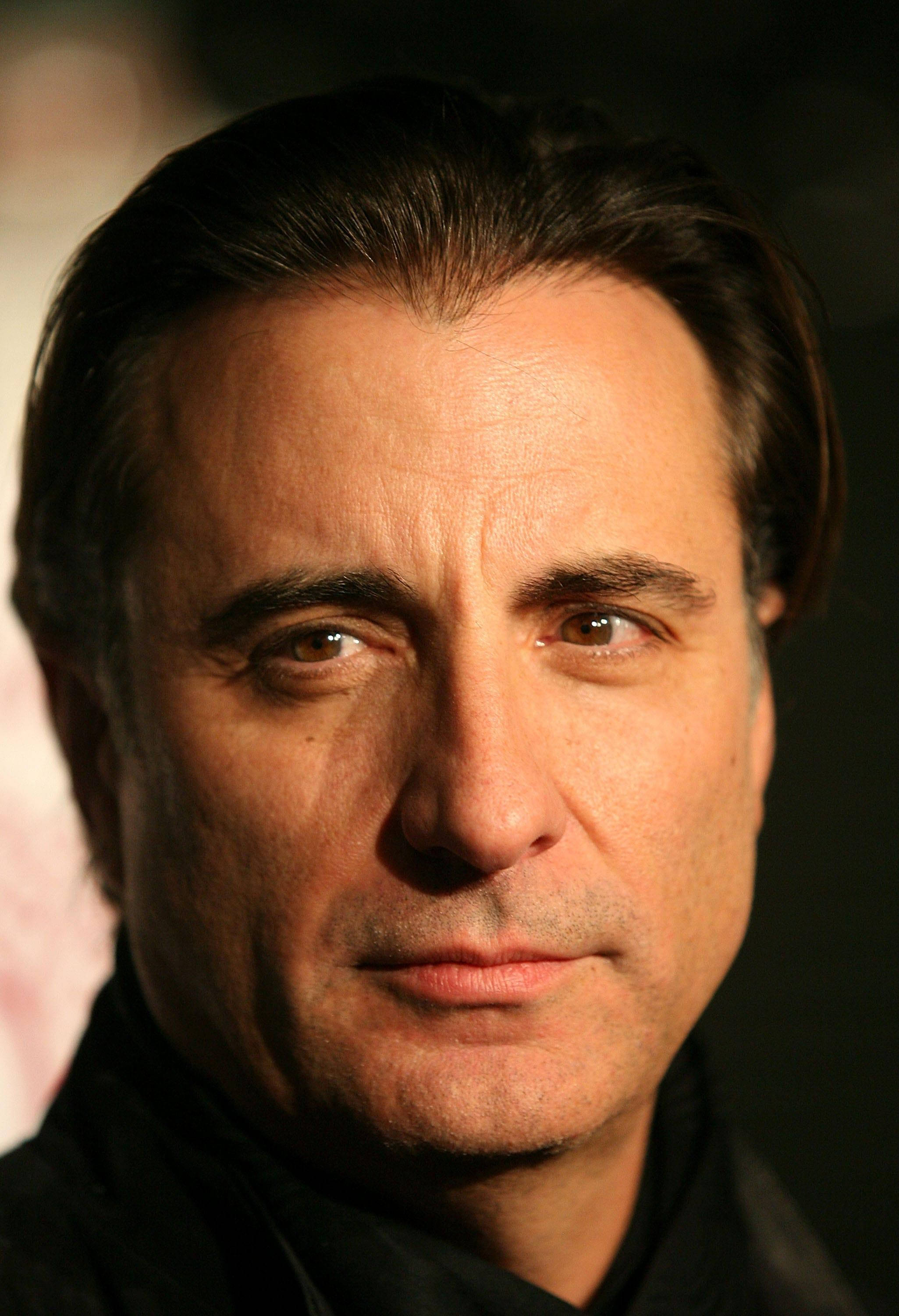 Andy Garcia 桌布 壁紙 — 特寫肖像，一名黑髮男子在溫暖聚光燈下，眼神銳利，背景深色。