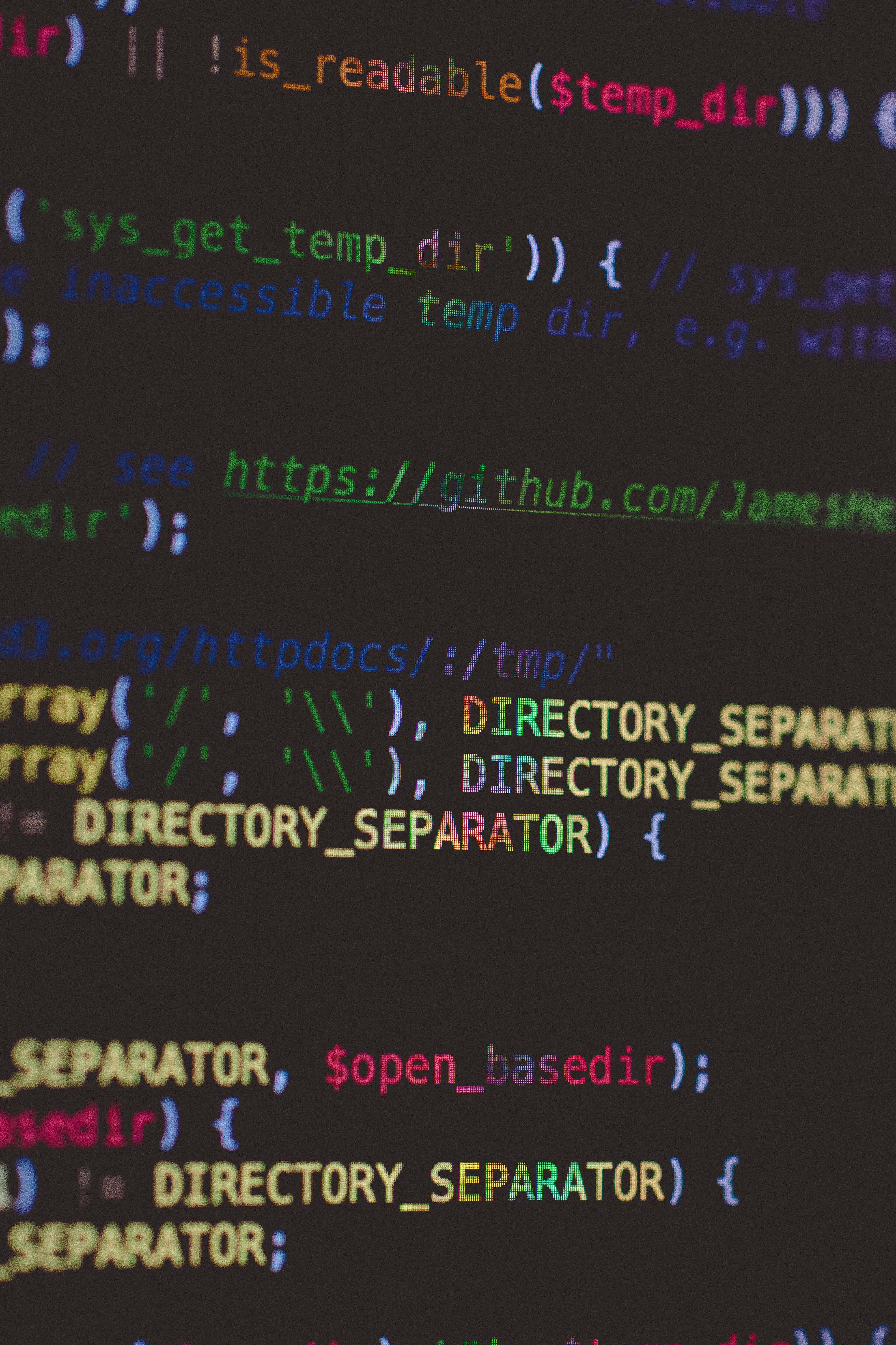 Code 桌布 壁紙 — 特寫色彩繽紛的語法高亮PHP程式碼在黑暗螢幕上滾動，背景模糊。